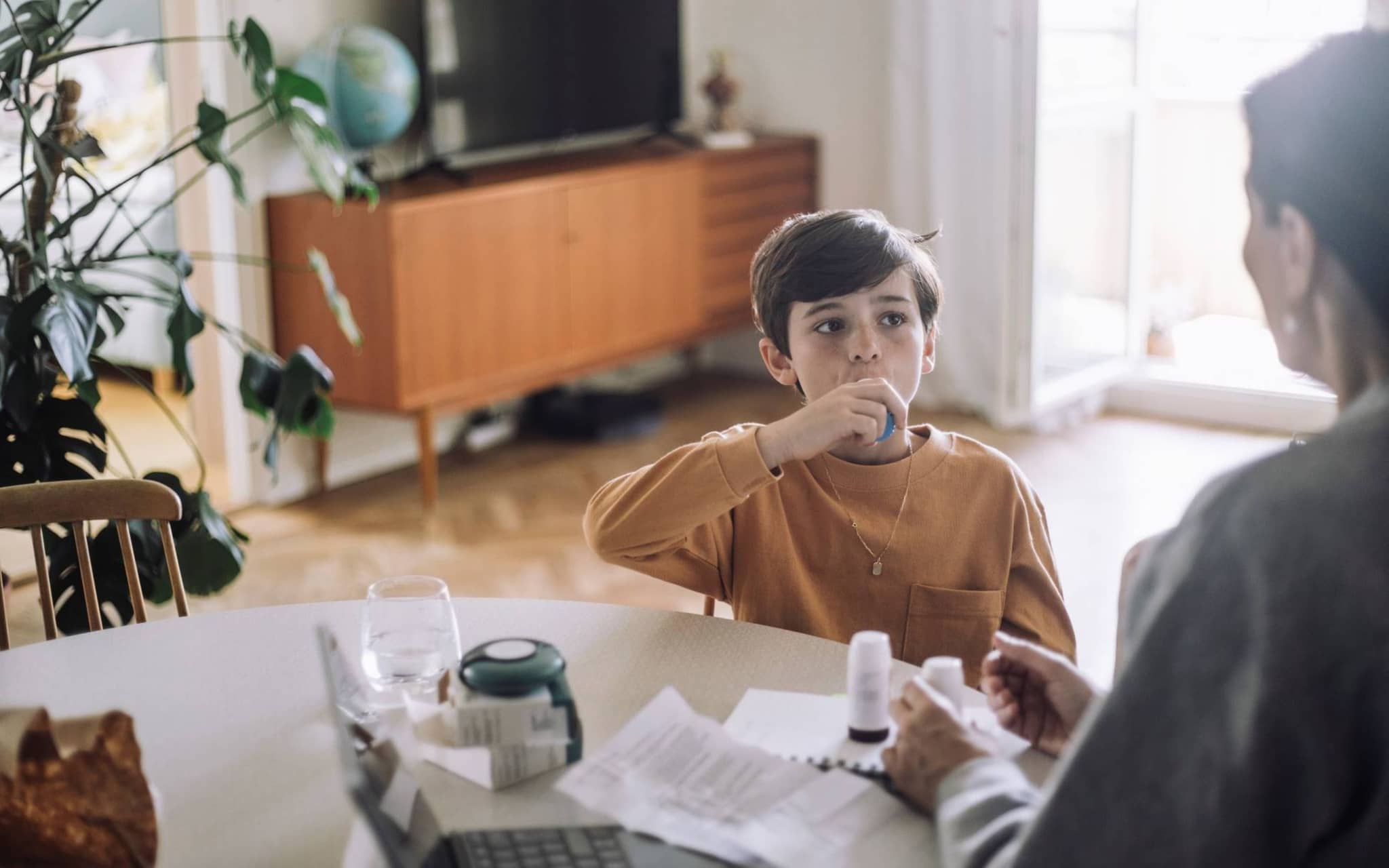 Asthma bei Kindern: Junge inhaliert am Tisch