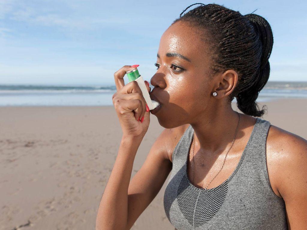 Asthma und Sport: Junge Frau nutzt Inhalator beim Laufen