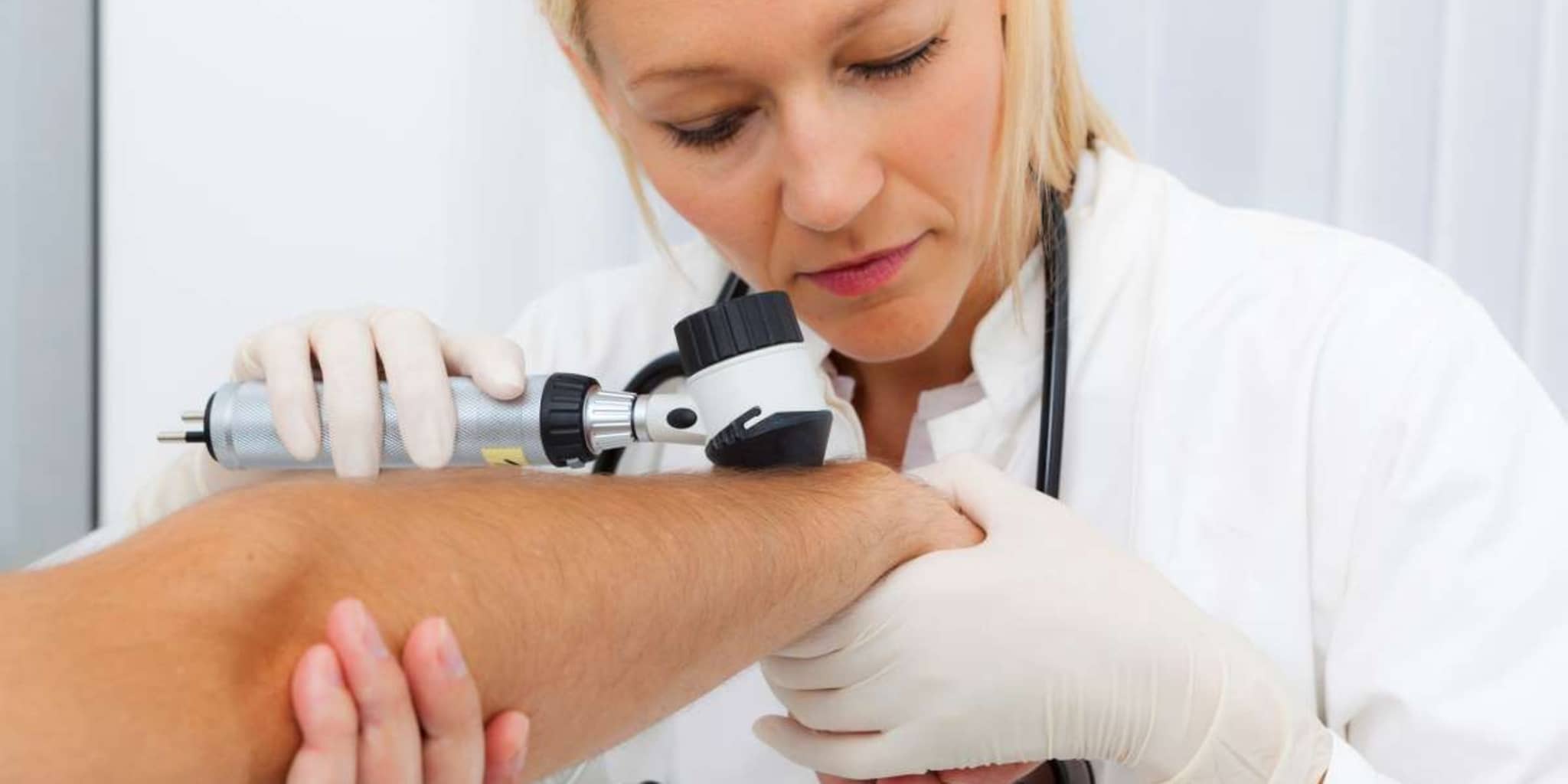 Hautkrebs-Screening: Ärztin untersucht die Haut eines Patienten mit dem Dermatoskop.