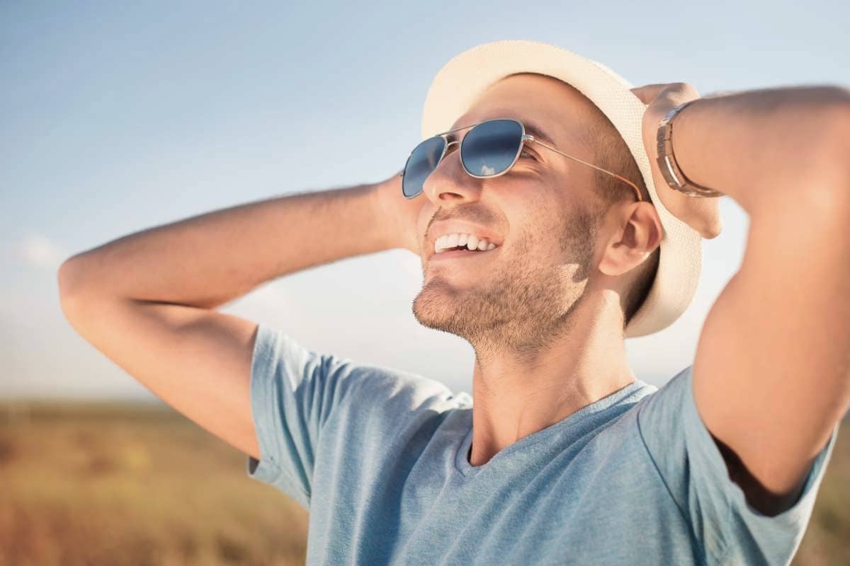 Hautkrebs-Screening: Junger Mann steht in der Natur und genießt die Sonne.