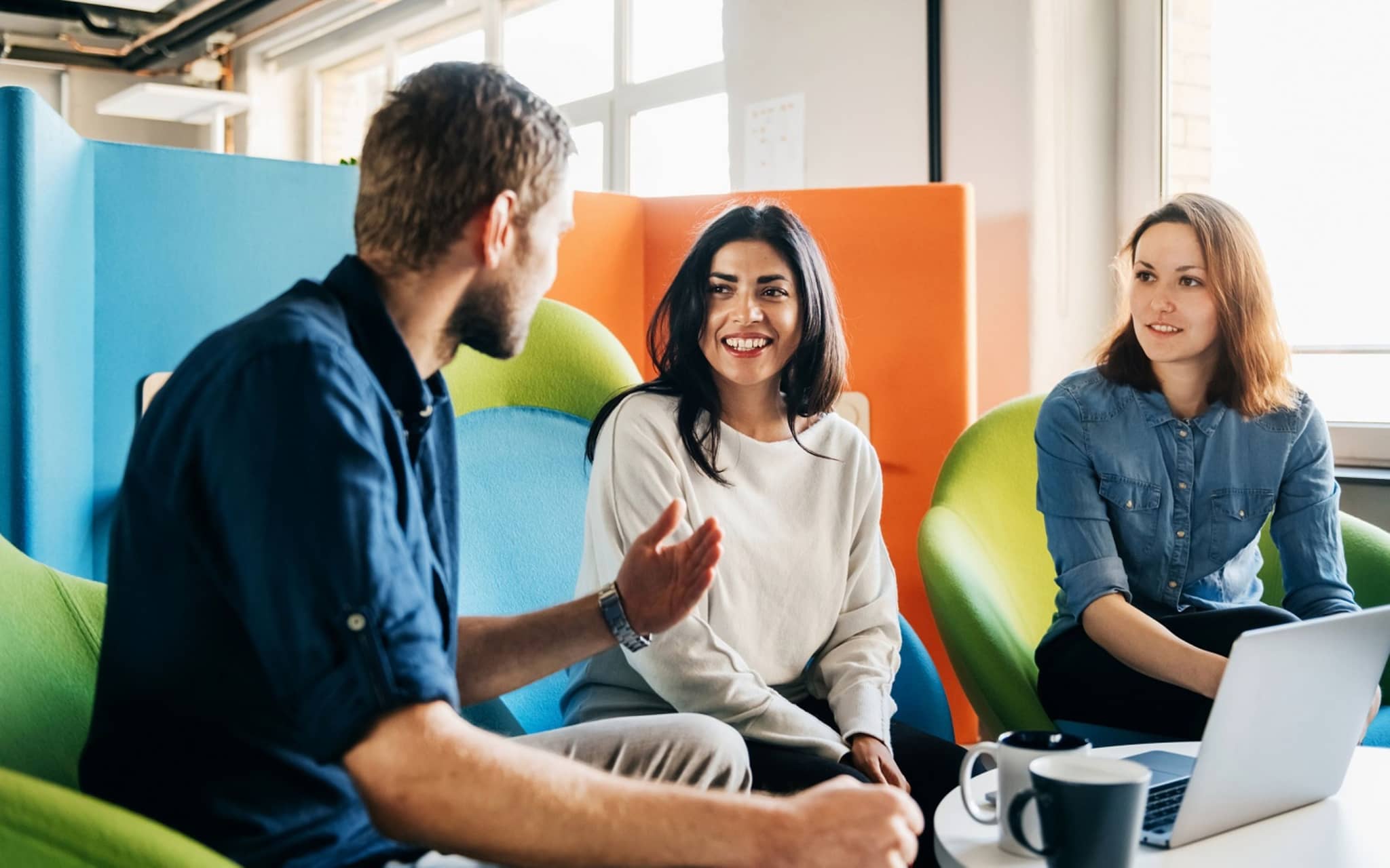 DAK-Akademie: Gruppe junger Menschen sitzt vor Laptop und unterhält sich angeregt.