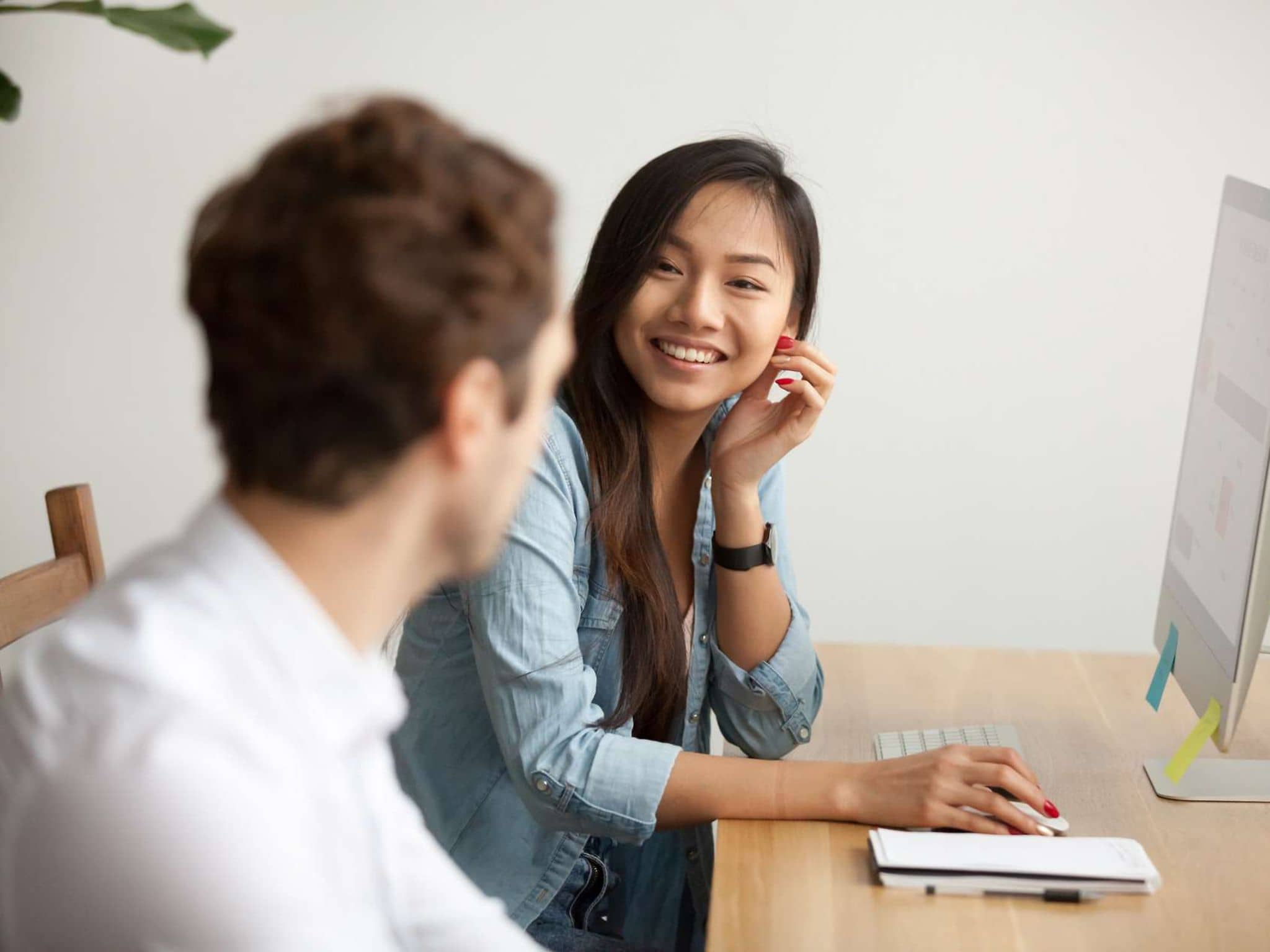 Bild: Junge Frau mit asiatischen Wurzeln im Gespräch mit einem Kollegen.