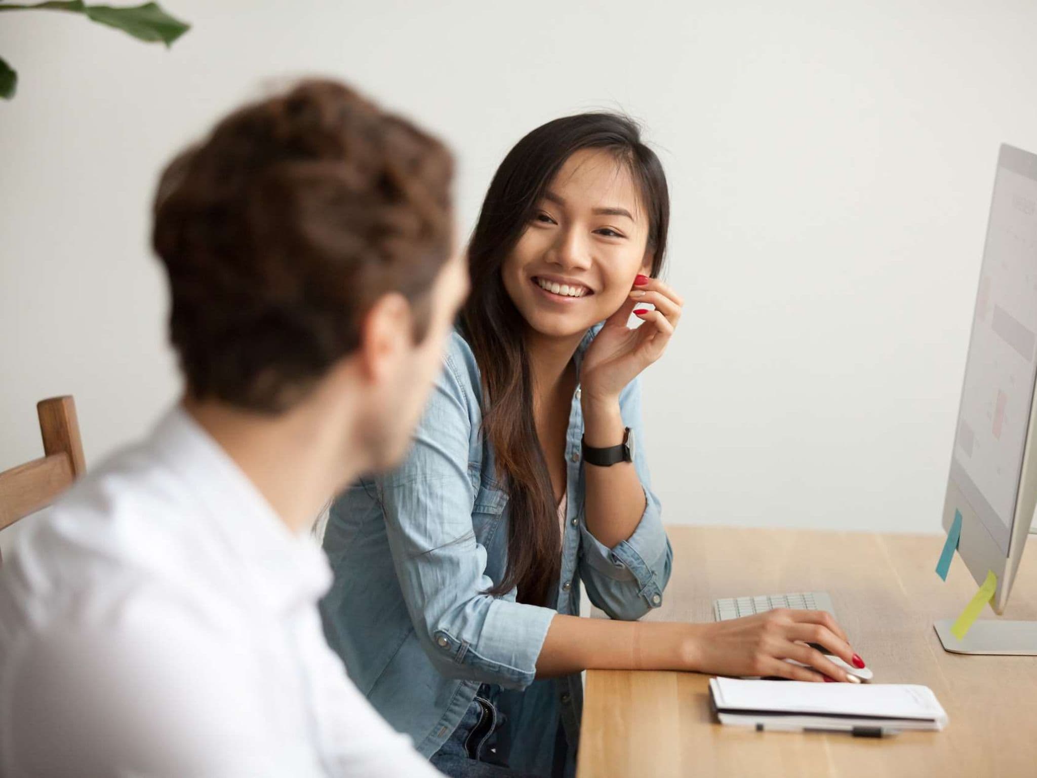 Bild: Junge Frau mit asiatischen Wurzeln im Gespräch mit einem Kollegen.