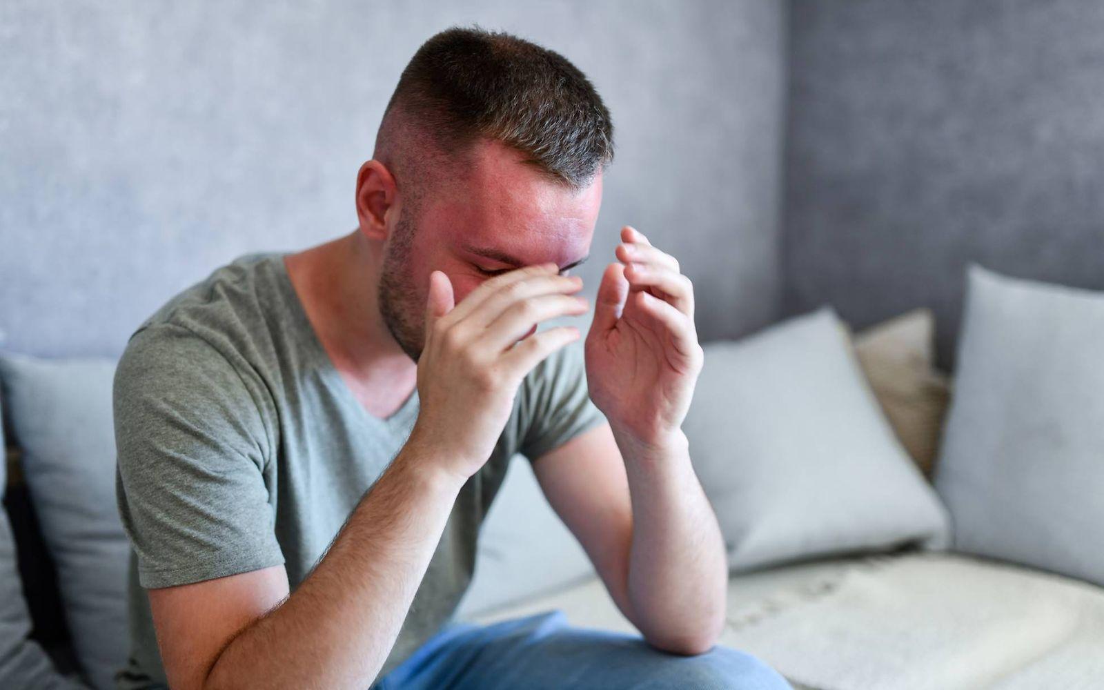 Hitzschlag: Mann sitzt mit hochrotem Kopf auf dem Sofa