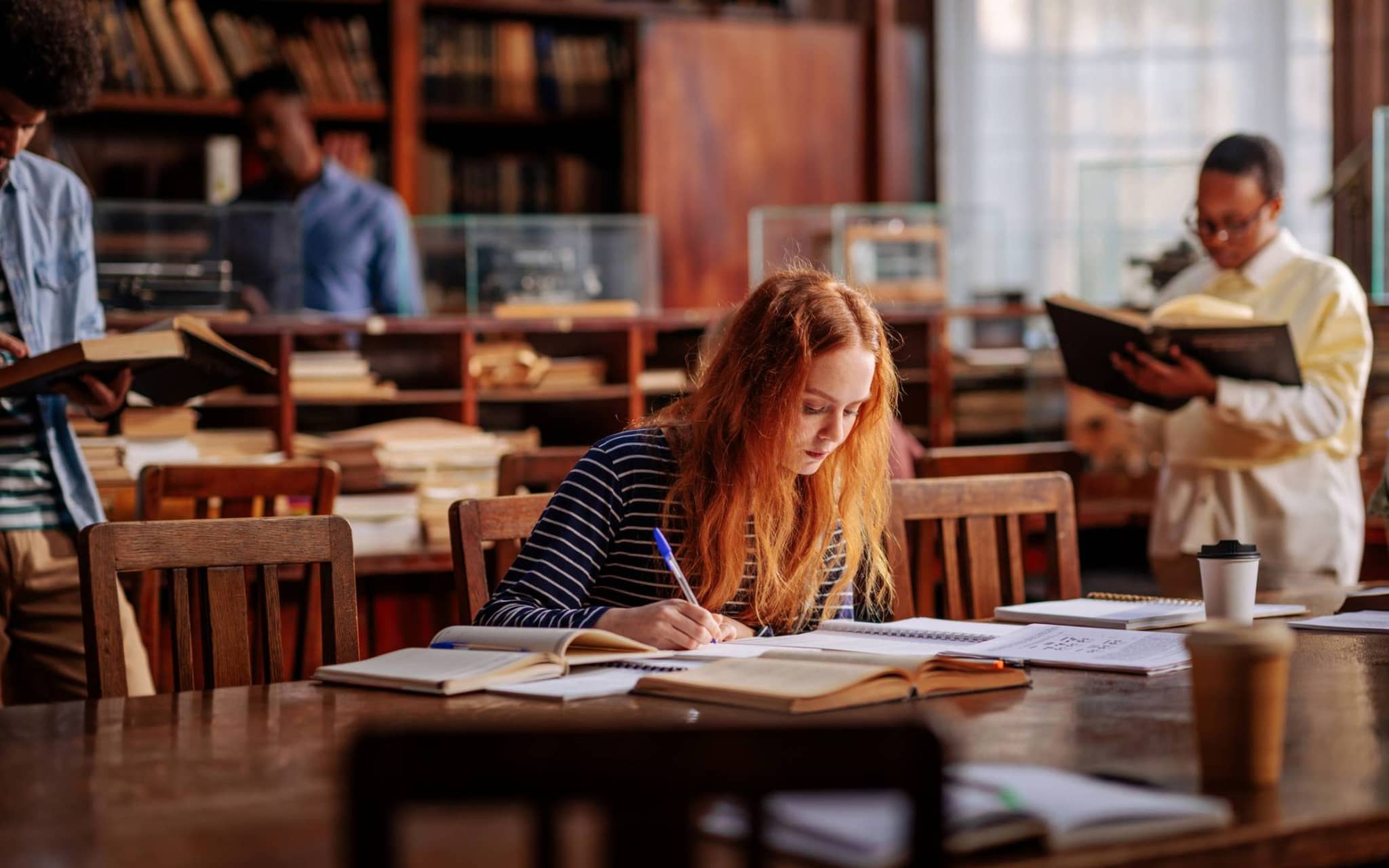 Krankenversicherung für Studenten aus dem Ausland: Junge Frau liest ein Buch in einer Bibliothek.