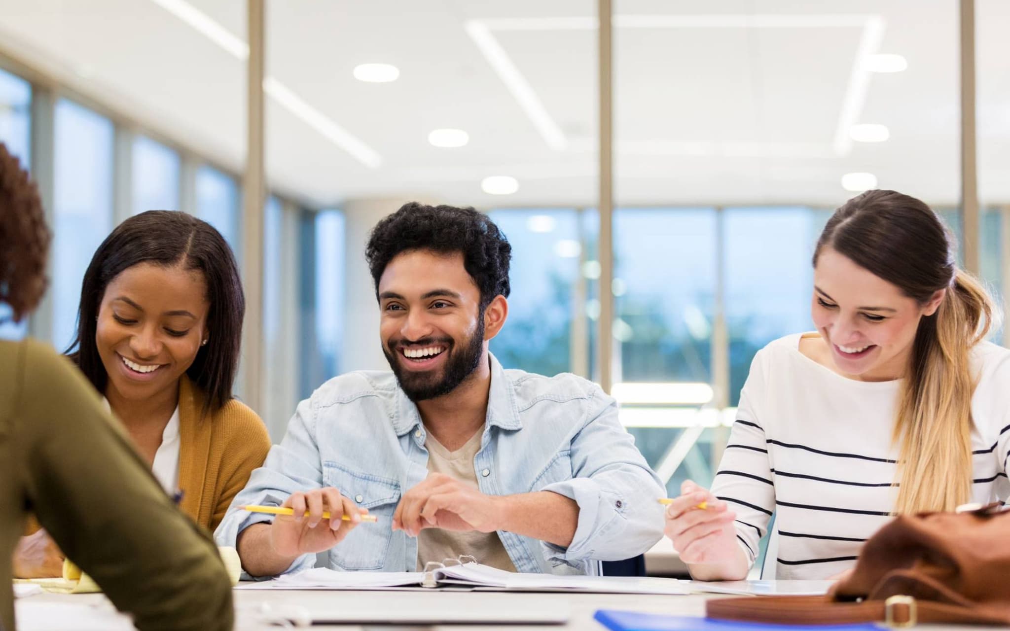 Gruppe Studierender sitzen an einem Tisch und lachen.