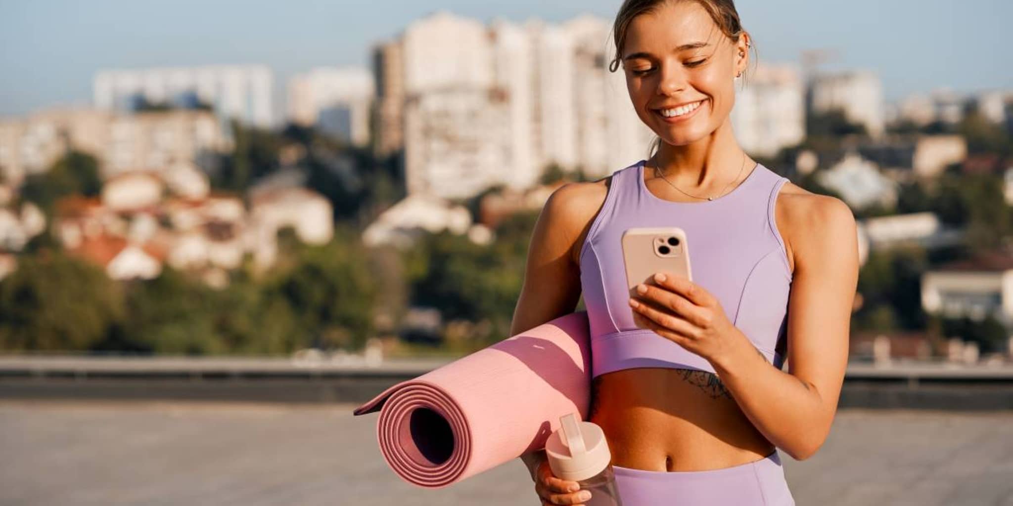 DAK Vorteilsrechner: Junge Frau in Sportkleidung schaut auf ihr Handy.