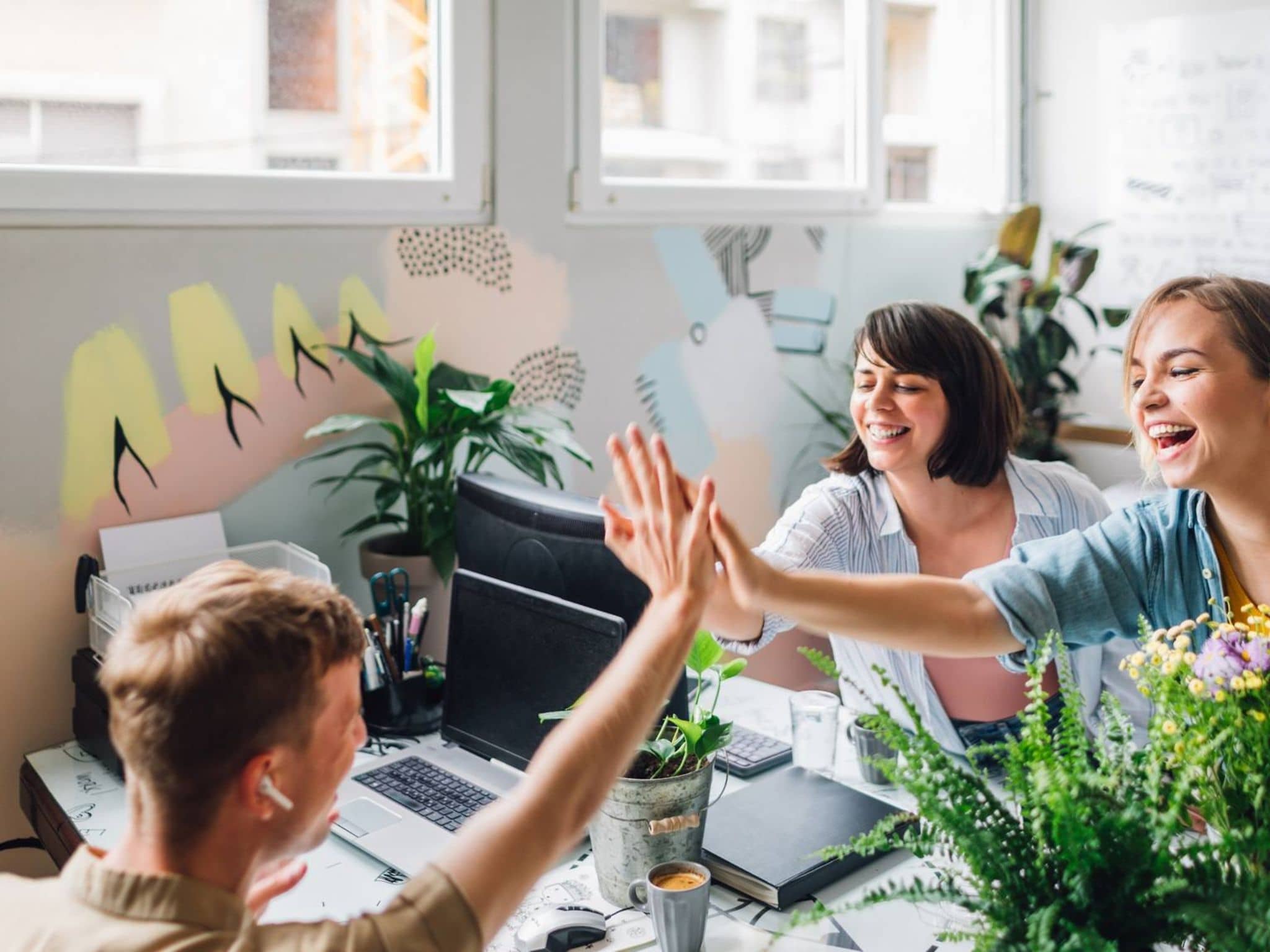 Bild: Kollege und Kollegin geben sich High-Five im Büro und lachen