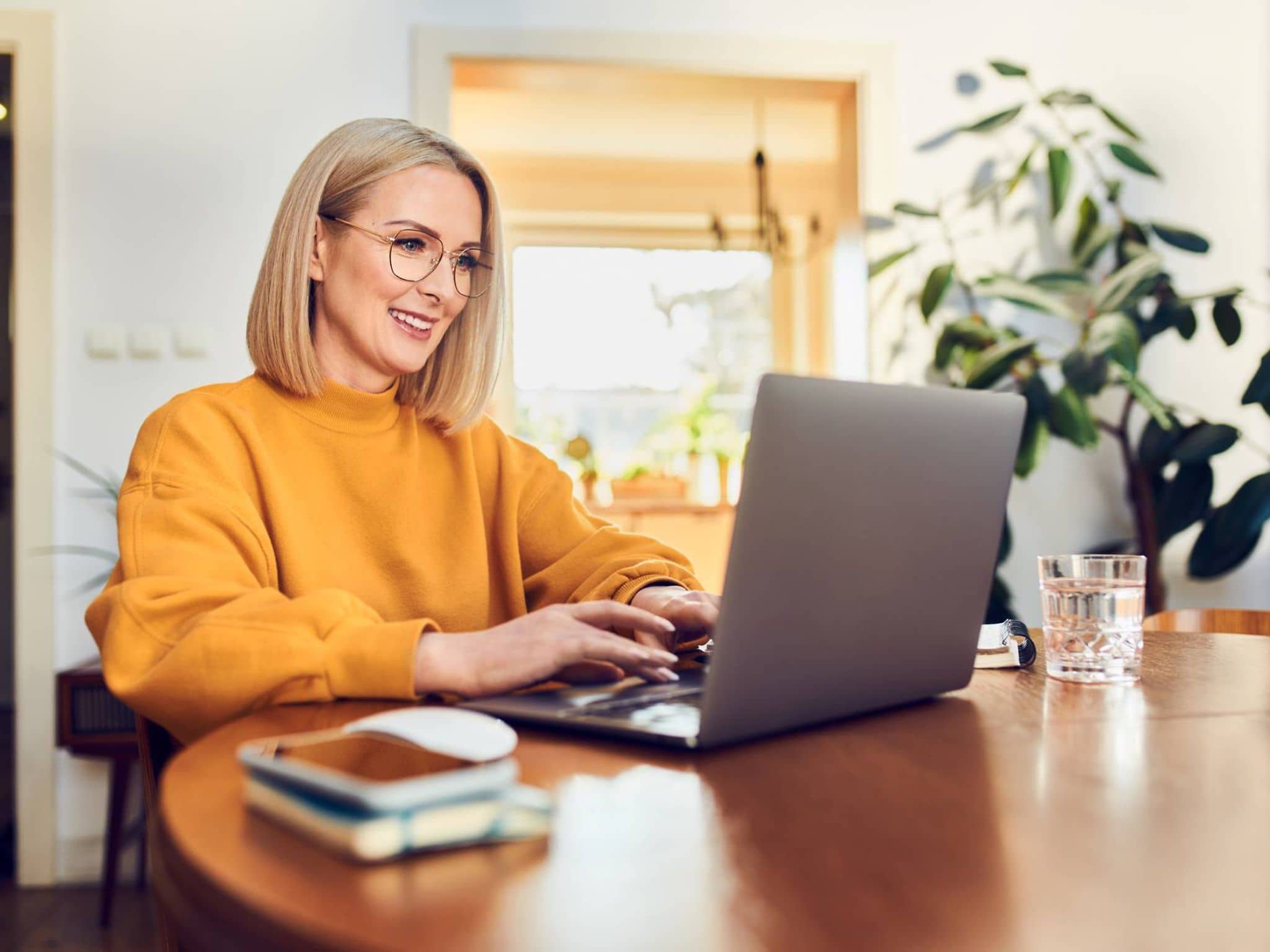 Gesetzliche Krankenversicherung für Selbstständige: Frau sitzt am Esstisch und arbeitet am Laptop