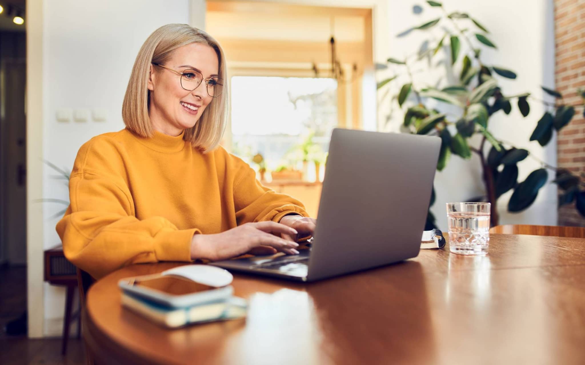 Gesetzliche Krankenversicherung für Selbstständige: Frau sitzt am Esstisch und arbeitet am Laptop