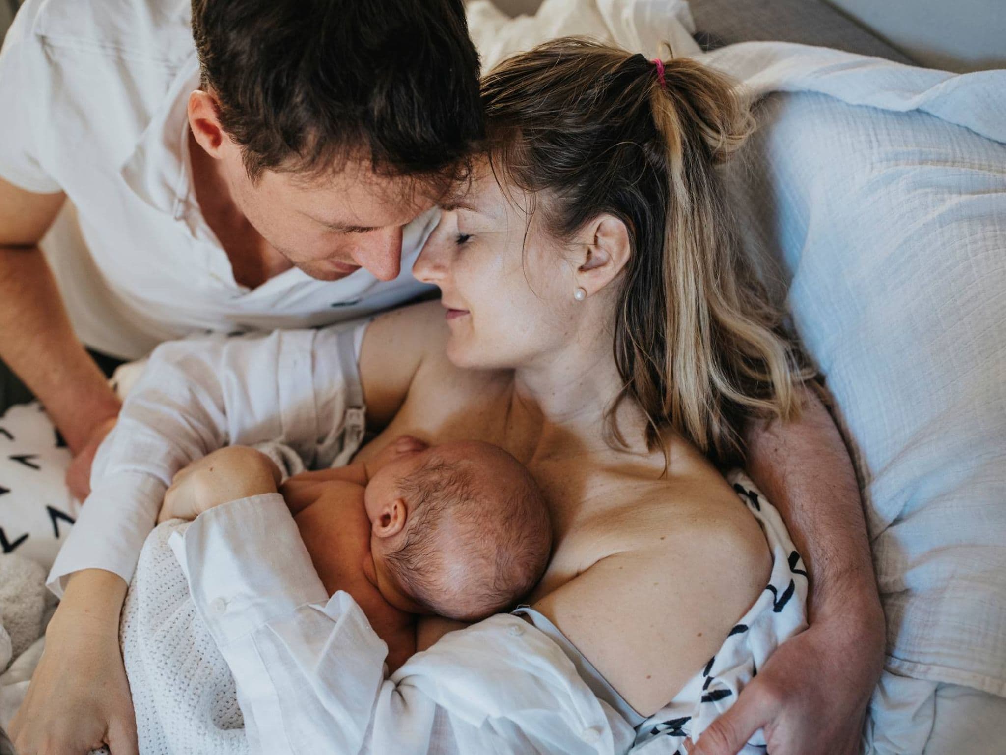 Symbolbild Ablauf einer Geburt: Eltern halten ihr Neugeborenes