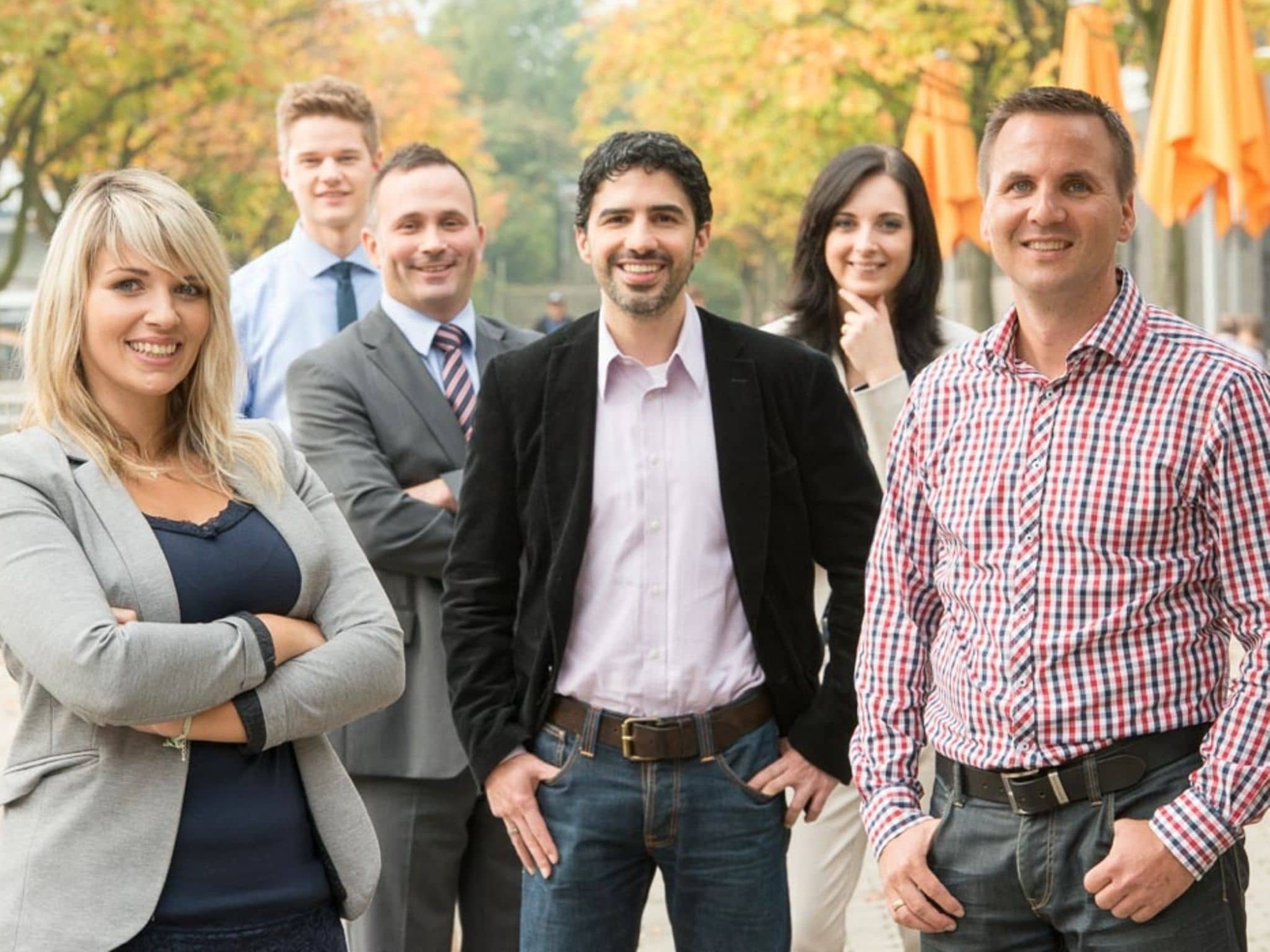 Mitarbeitende der DAK-Gesundheit lächeln stehend in die Kamera.