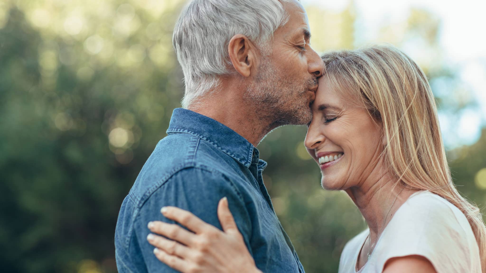 Älter werden: Ein senoriger Mann küsst einer Frau auf die Stirn
