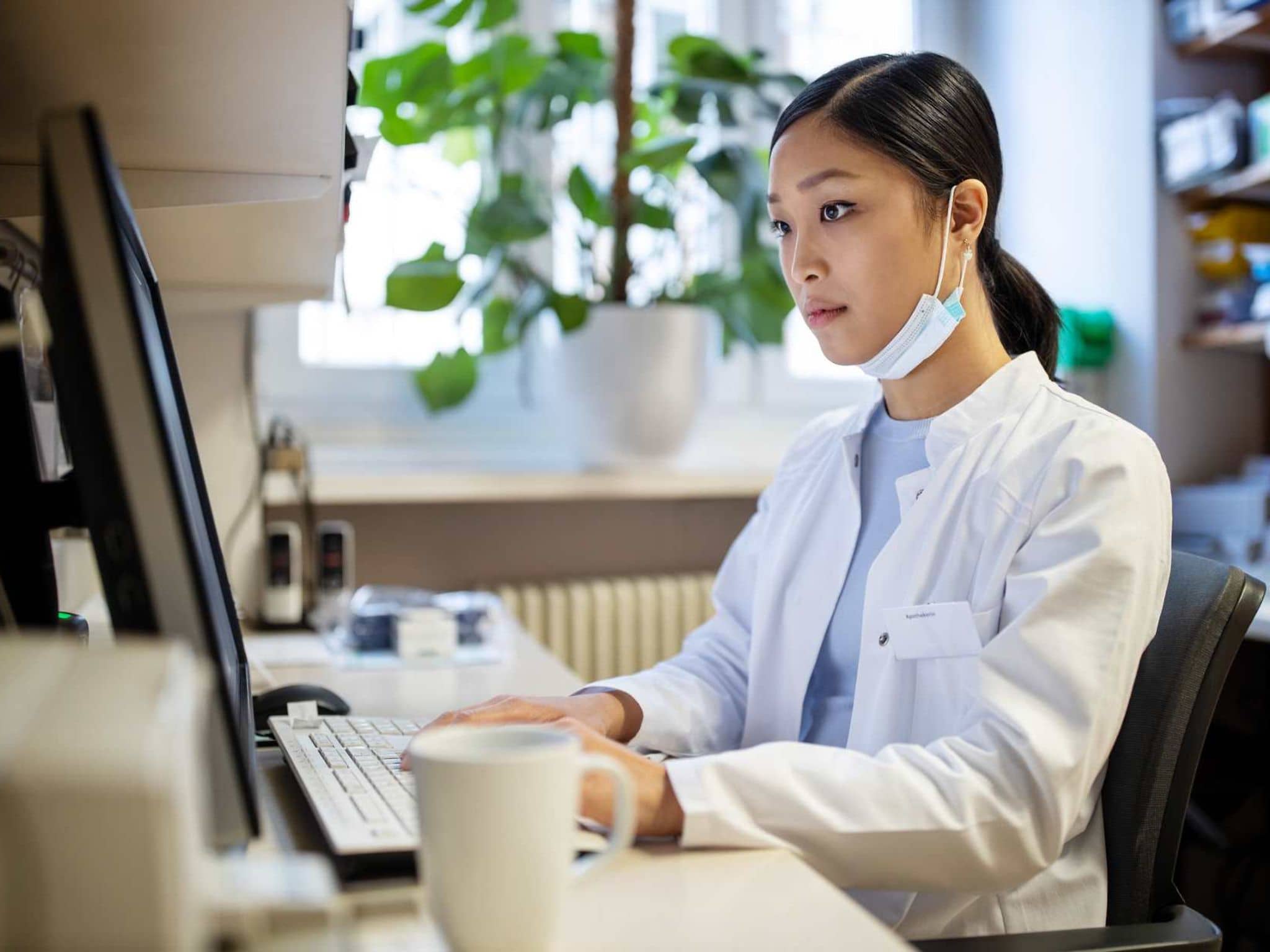 Bild: Eine Apothekerin sitzt an einem Computer und schaut auf den Bildschirm.