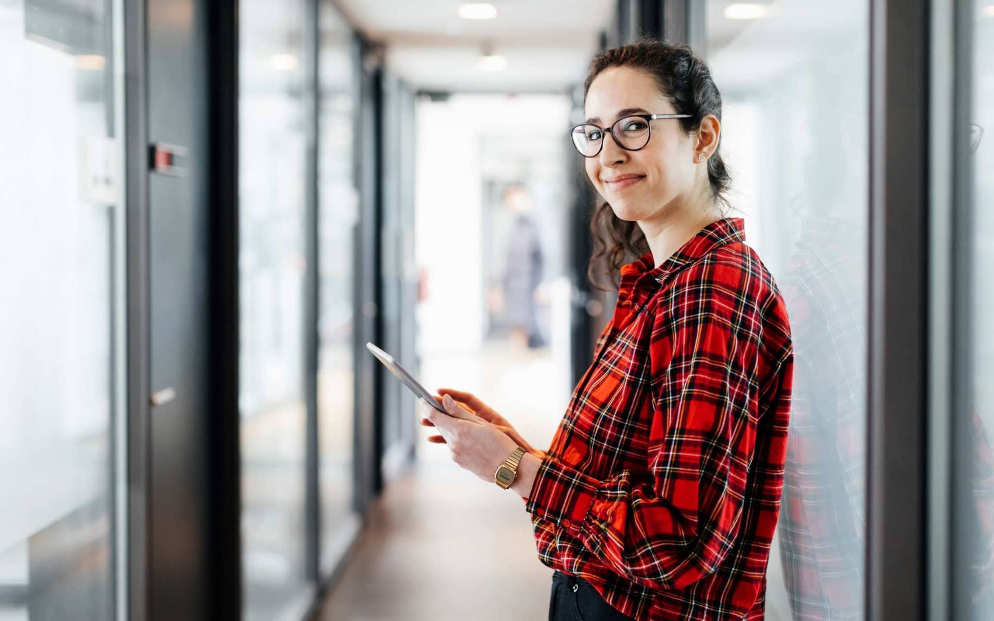 Bild: Frau mit Tablet steht in einem Gang.