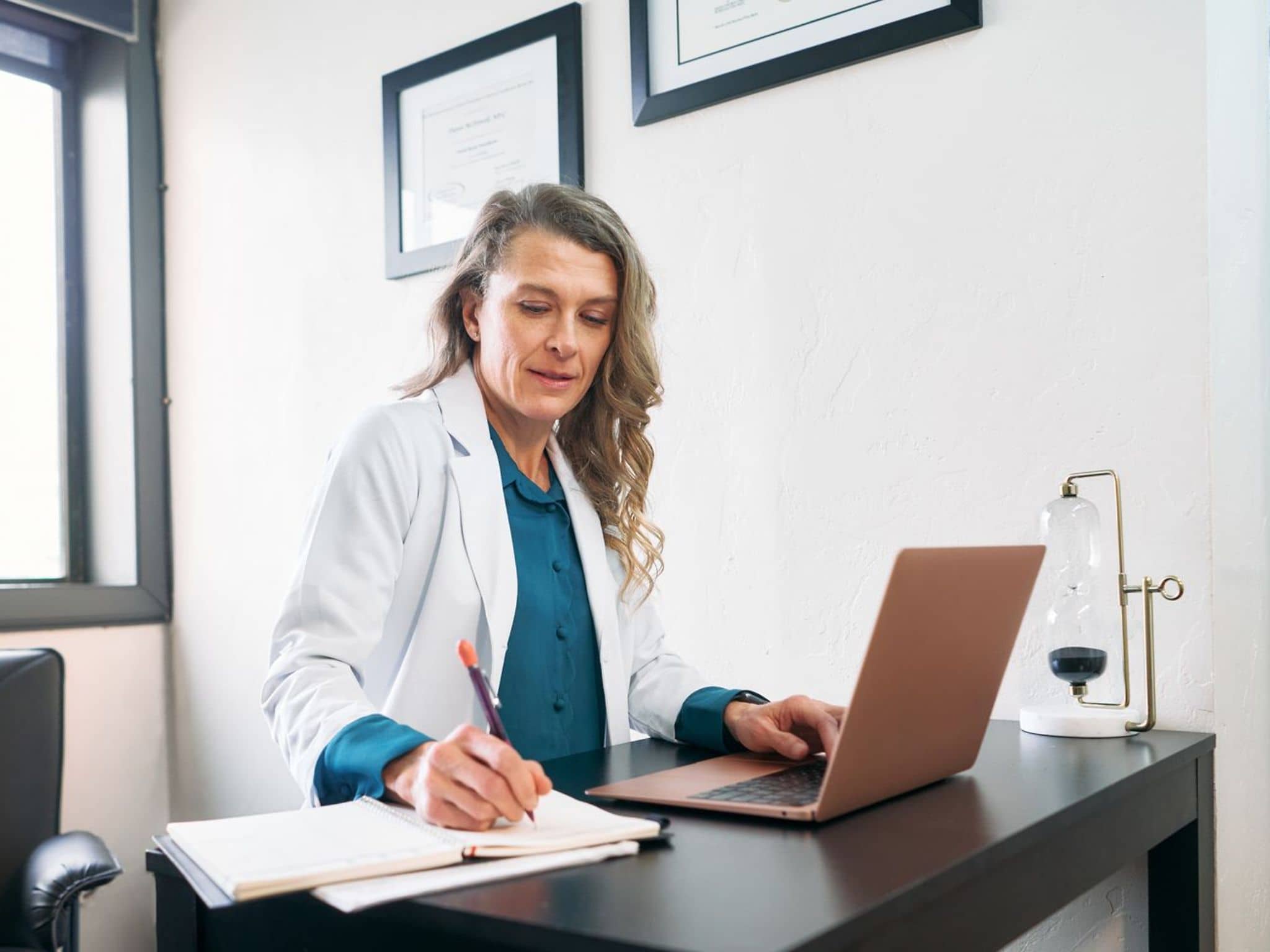 Bild: Ärztin sitzt am Schreibtisch und schaut aktuelle Infos nach.