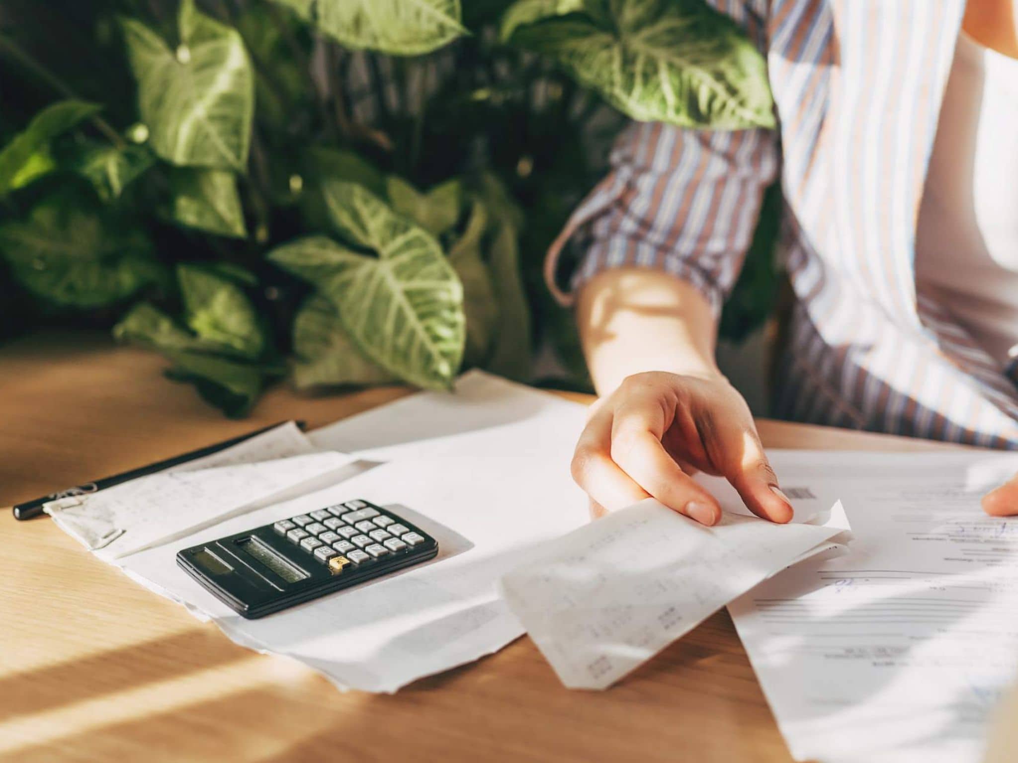 Bild: Frau schaut Rechnungsunterlagen durch und rechnet etwas mit einem Taschenrechner