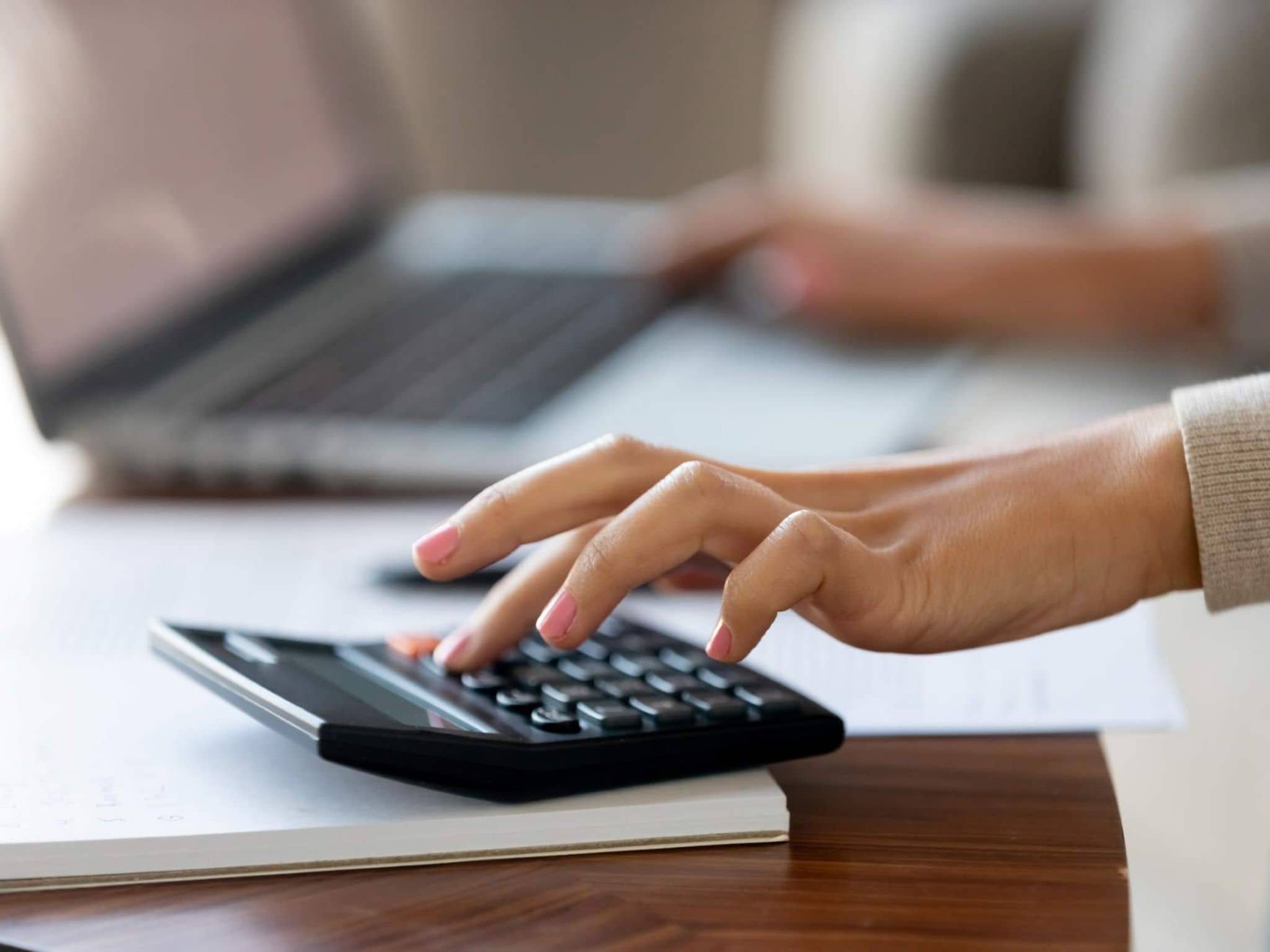 Bild: Frau mit rosa lackierten Fingernägeln tippt auf einem Taschenrechner