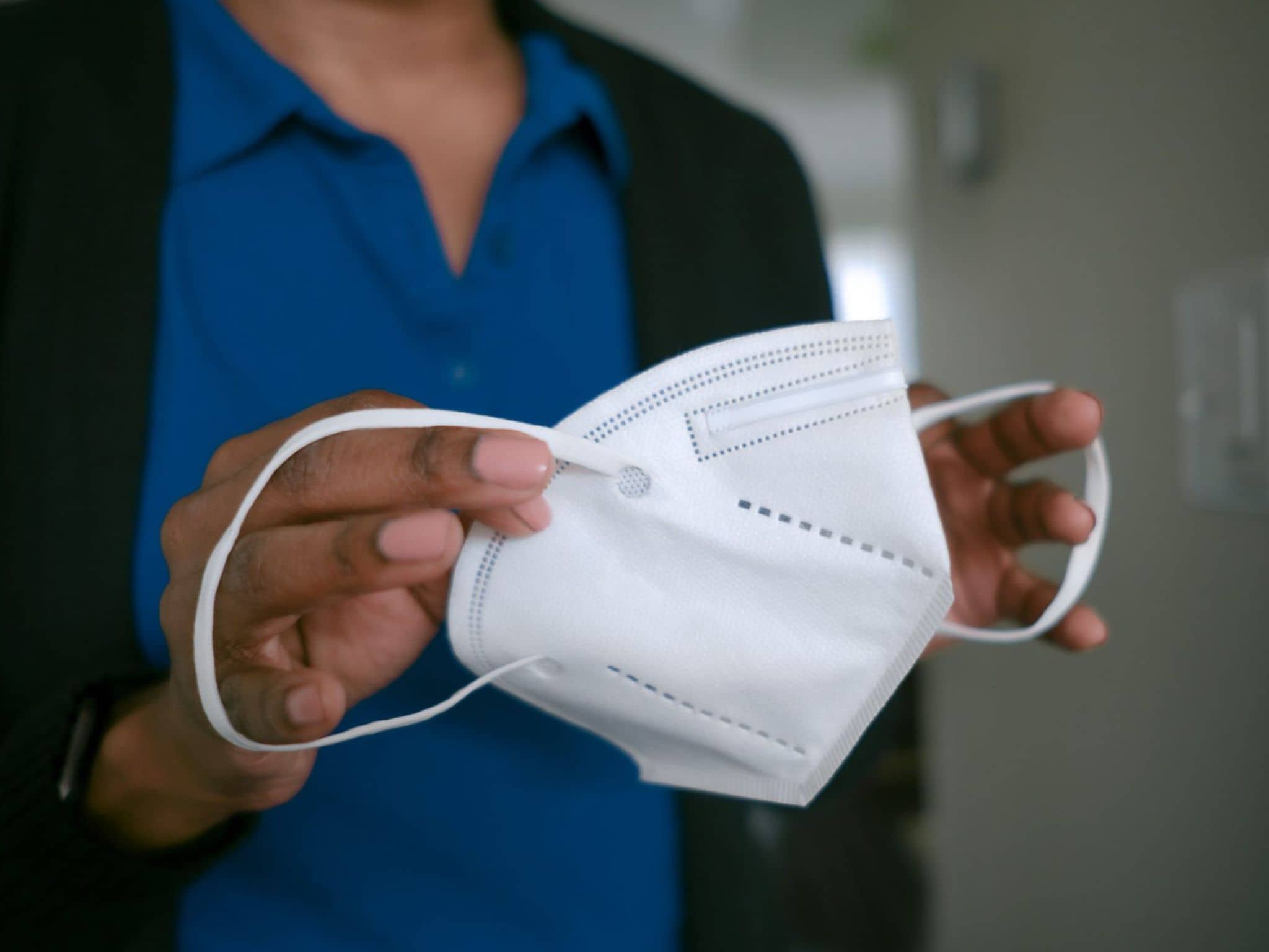 Bild: Pflegekraft setzt sich eine FFP2-Maske auf