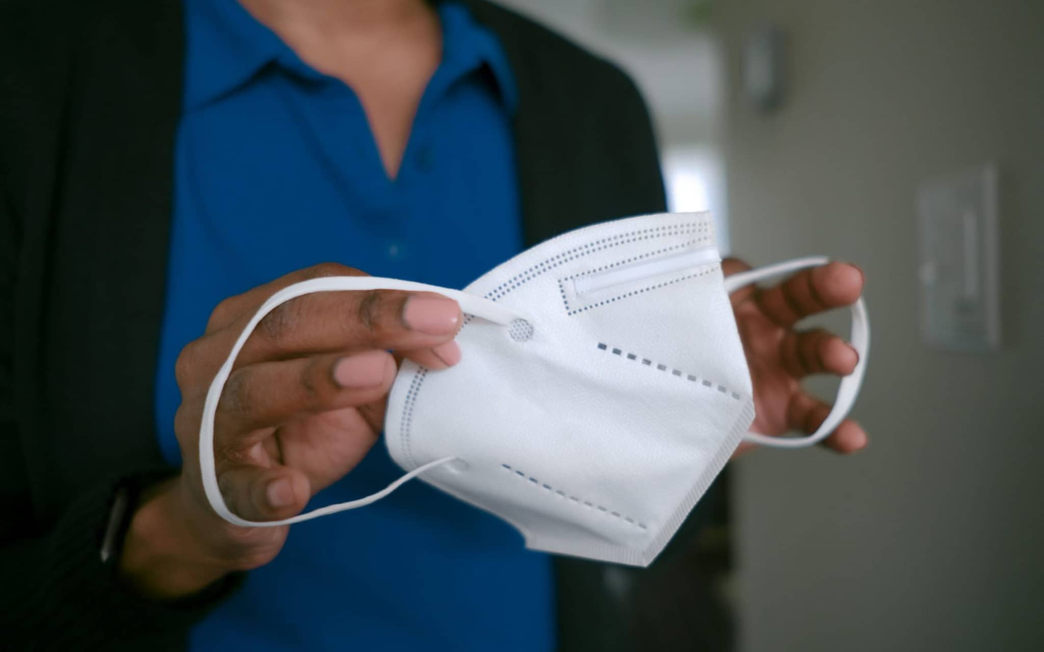 Bild: Pflegekraft setzt sich eine FFP2-Maske auf