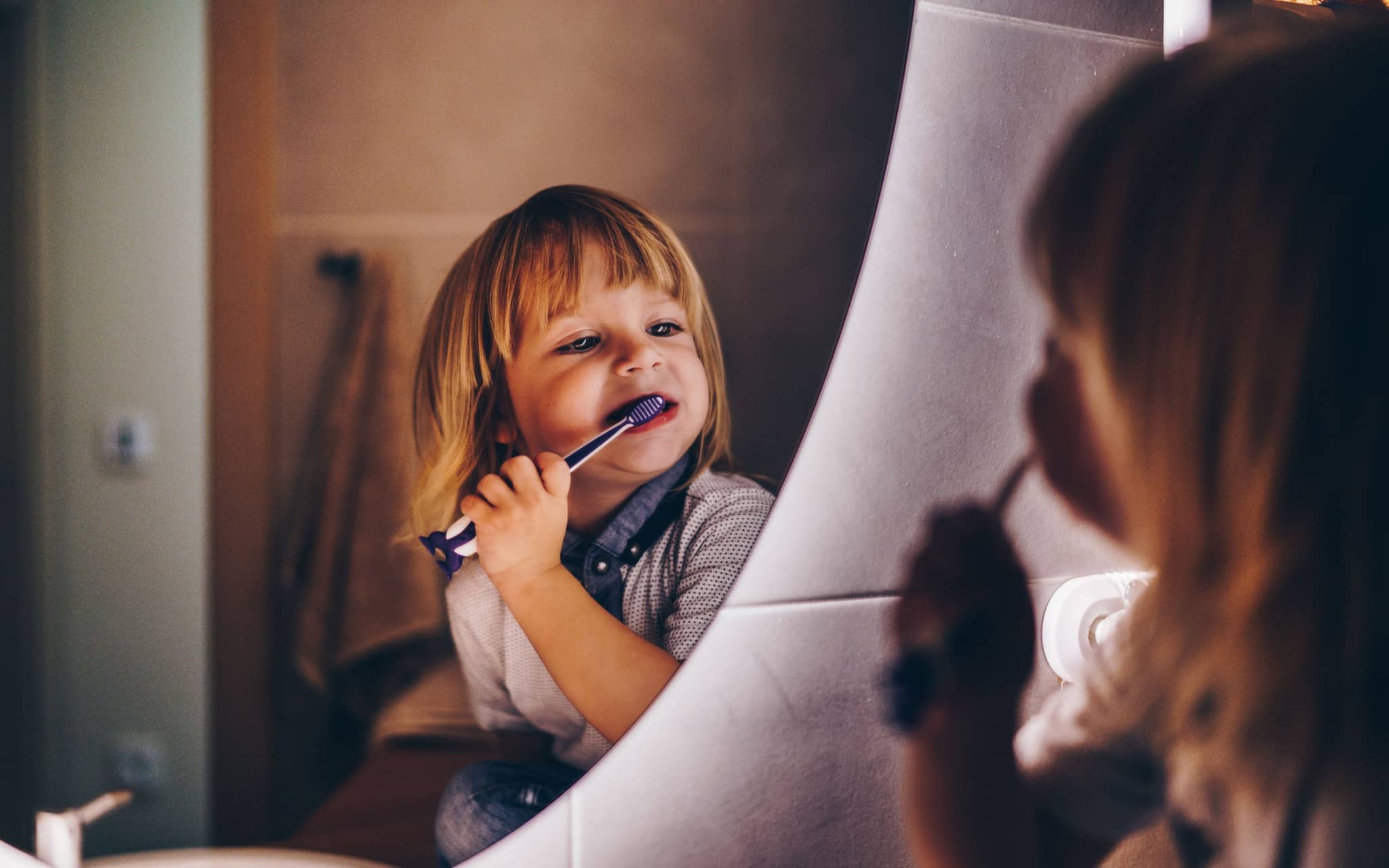 Kleinkind steht vor dem Spiegel und putzt sich die Zähne.