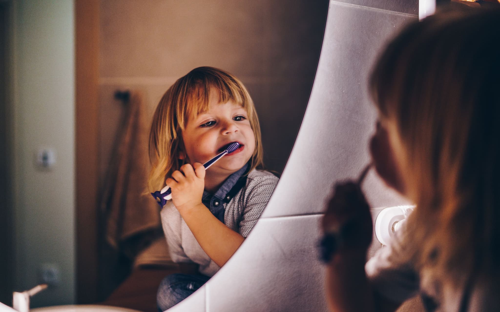 Kleinkind steht vor dem Spiegel und putzt sich die Zähne.