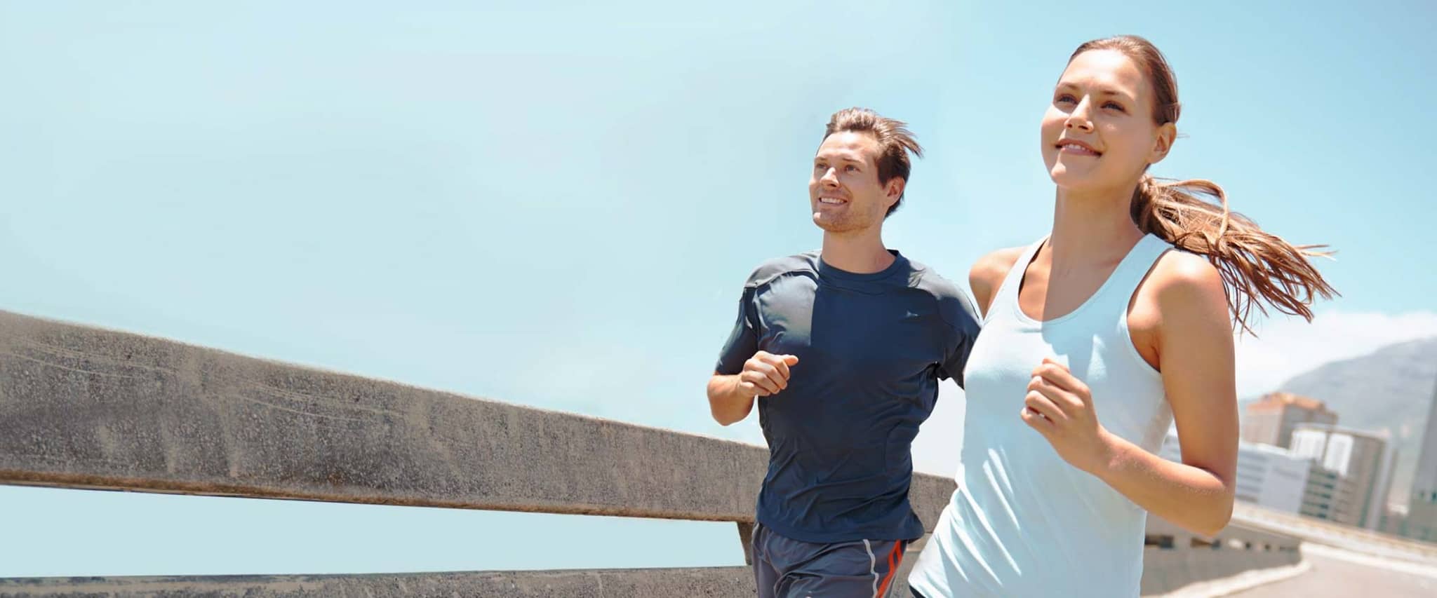 Fit & Cash: Mann und Frau joggen bei strahlendem Sonnenschein.