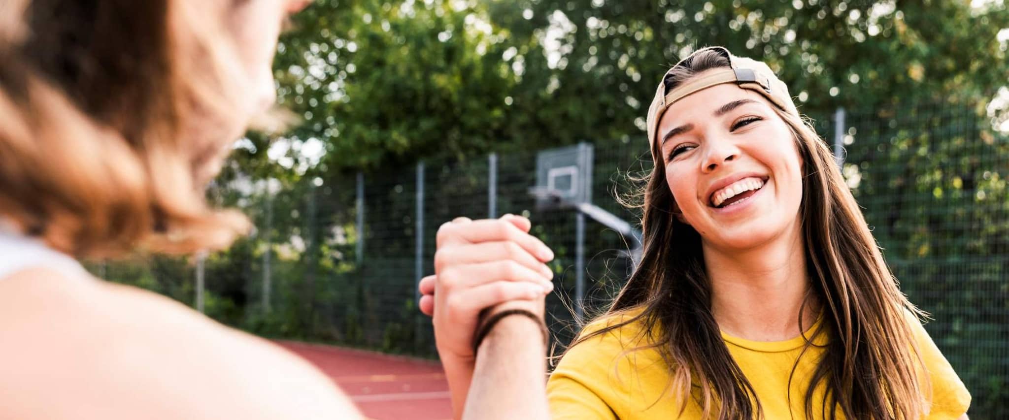 Bild: Teenagerin reicht einem Mitspieler die Hand nach einem Basketballspiel.