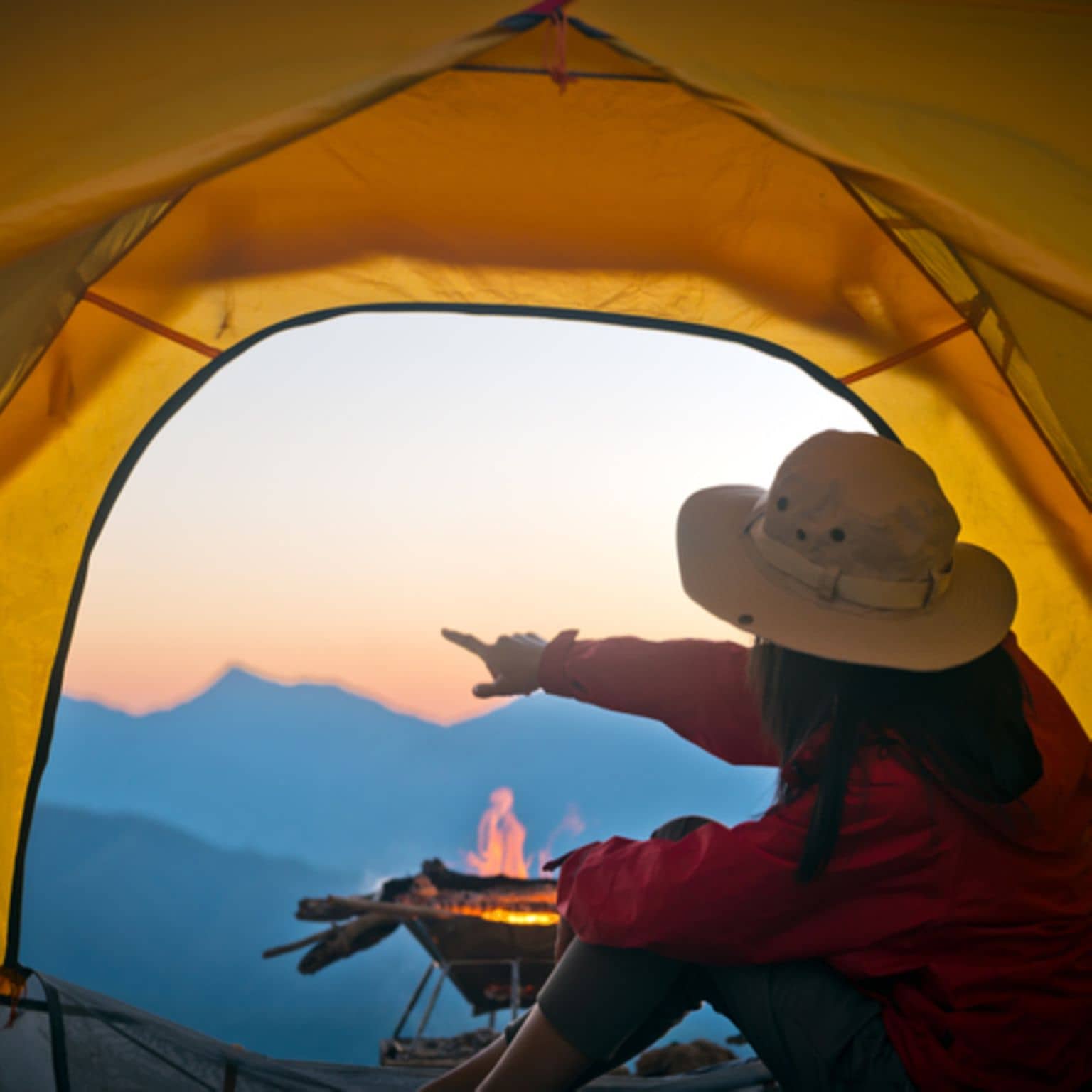 Frau sitz im Zelt und zeigt in die Ferne