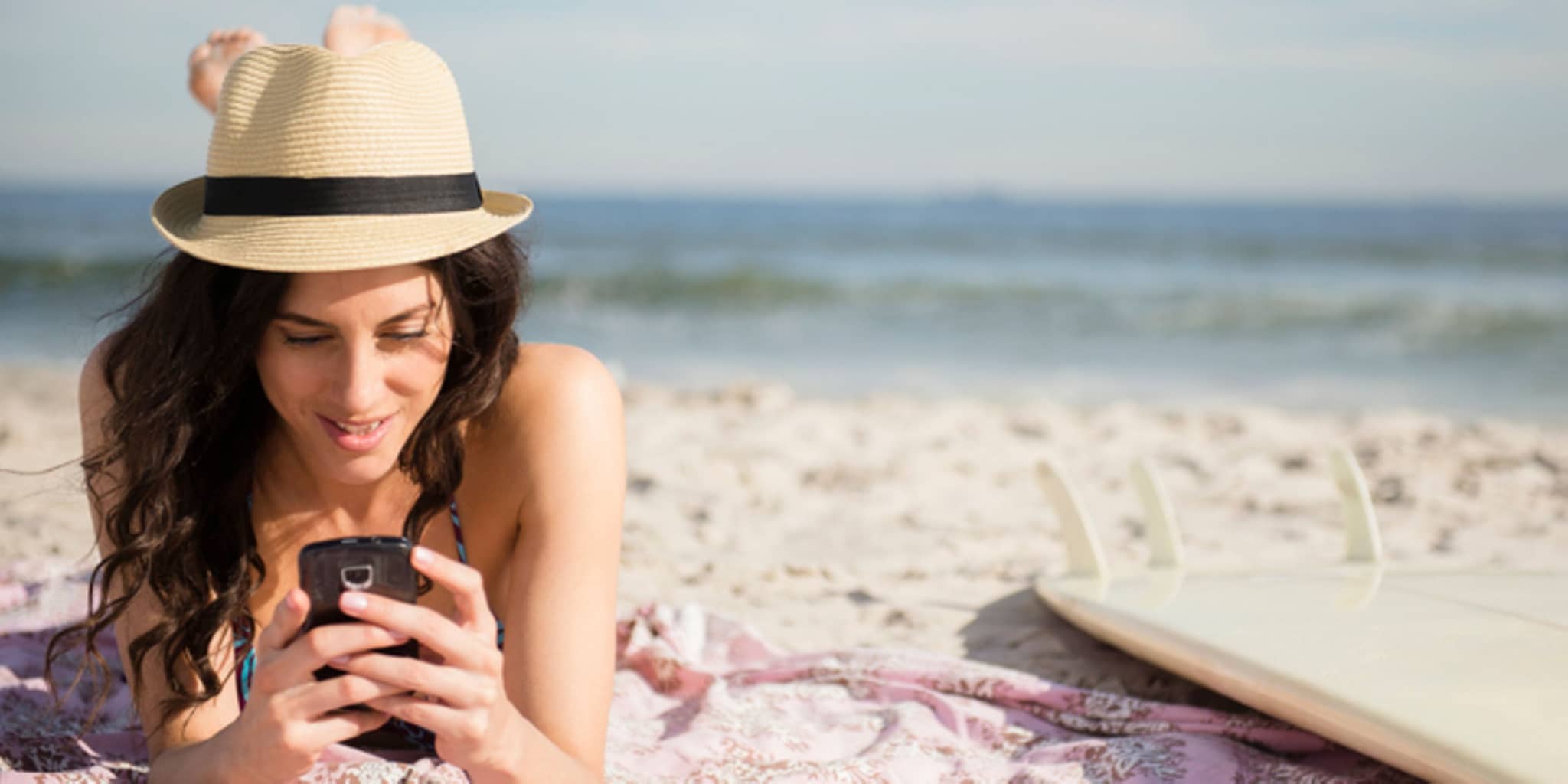 Junger Mann lehnt an Mauer und tippt etwas in sein Smartphone