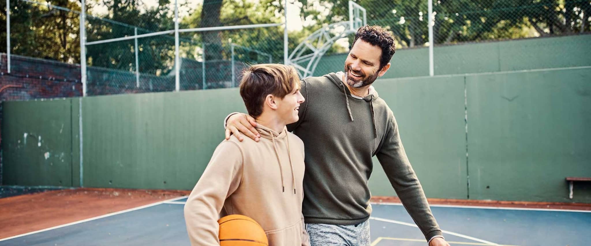 DAK-Bonusprogramm: Vater und Sohn gehen auf einem Basketballfeld.