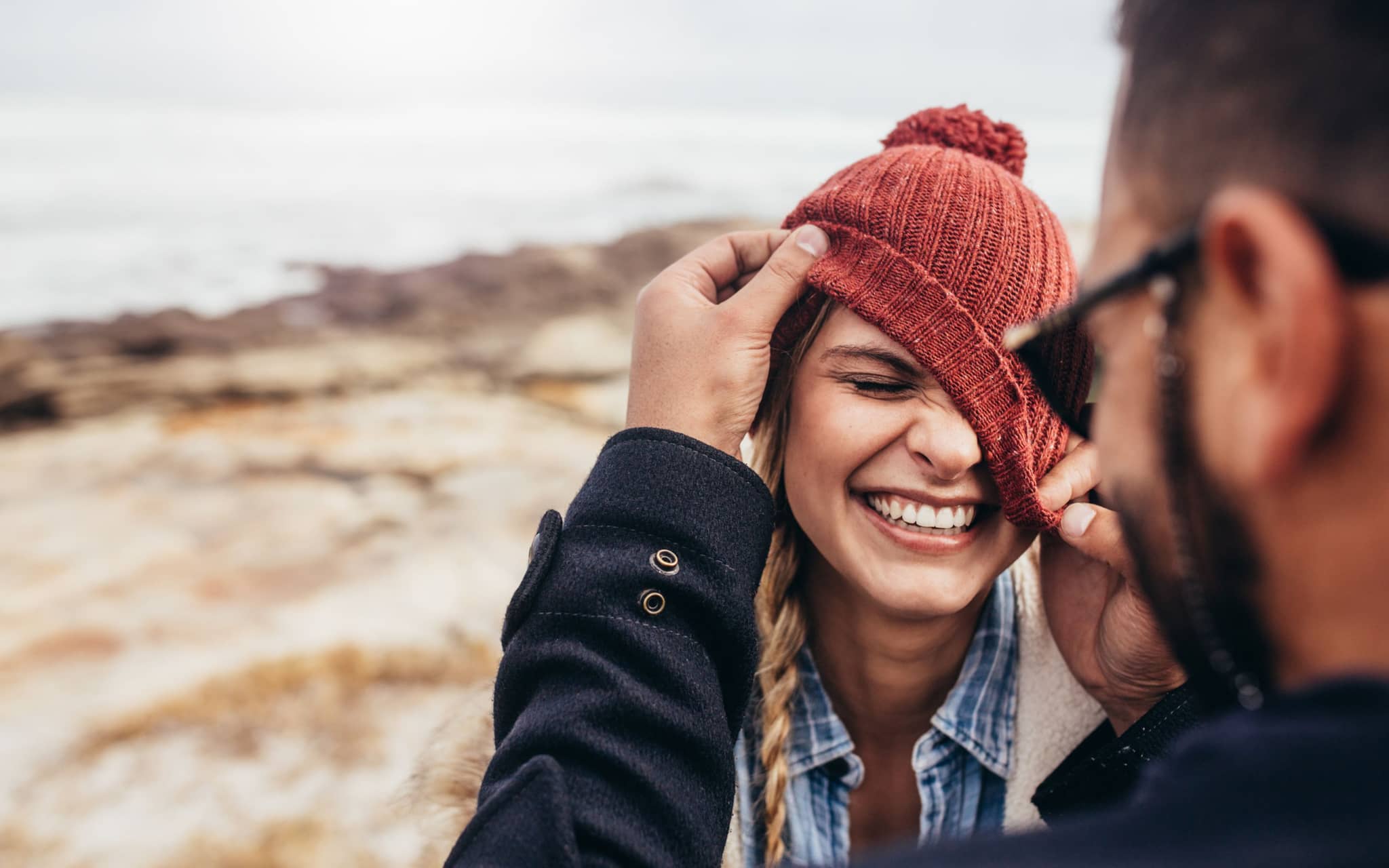 Frau trägt Mütze schief und grinst breit.
