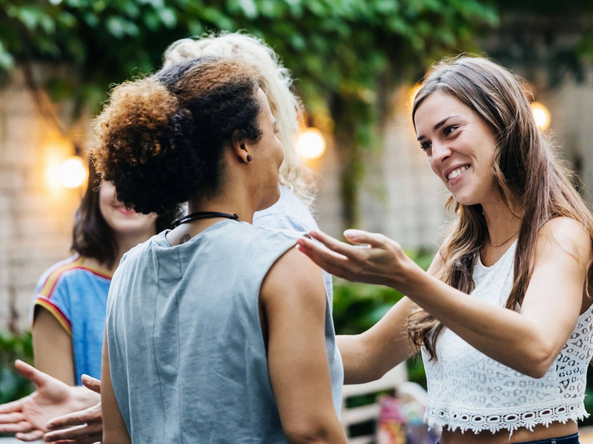 Zwei Frauen begrüßen sich freundlich auf einer Gartenparty voller Toleranz