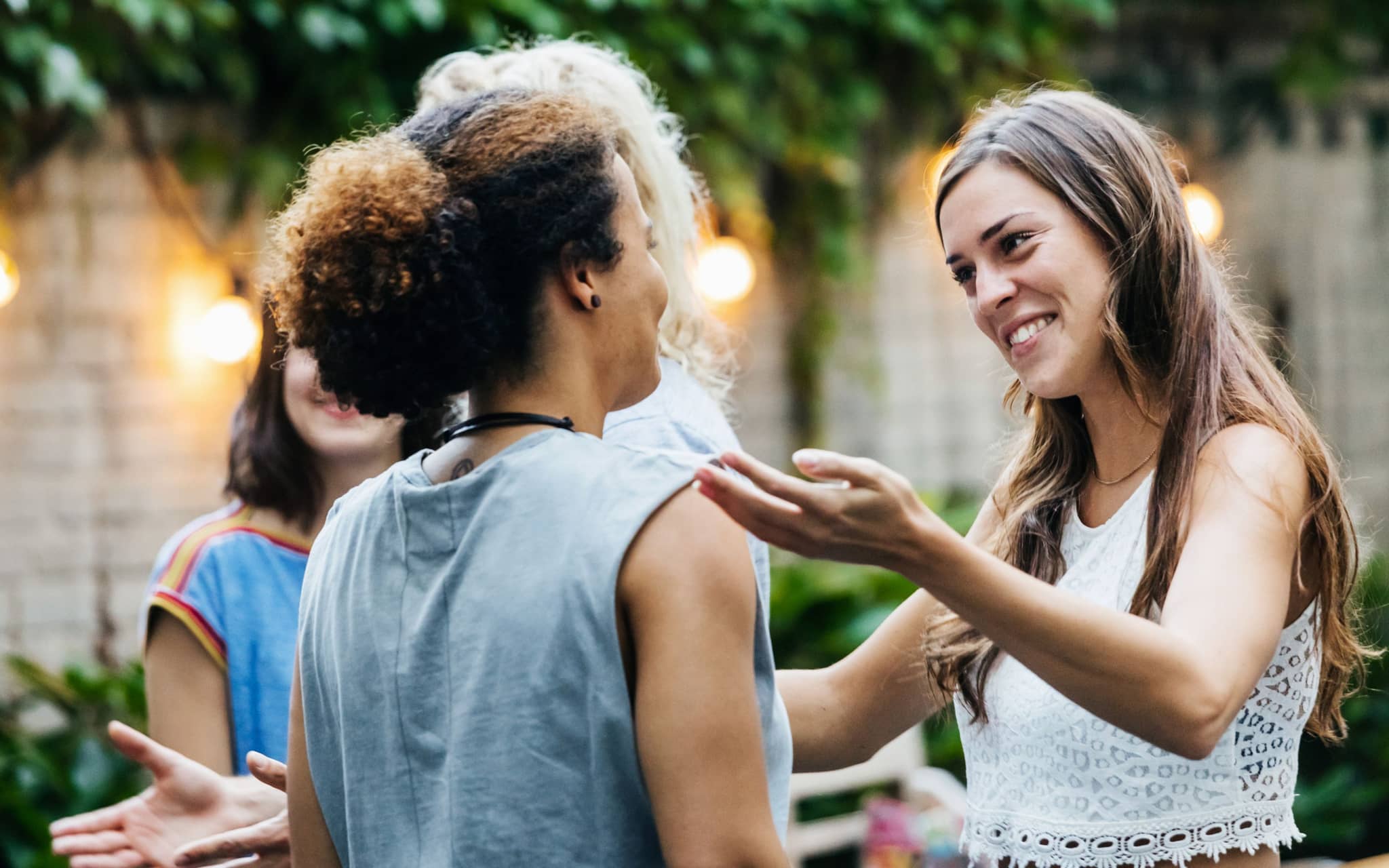 Zwei Frauen begrüßen sich freundlich auf einer Gartenparty voller Toleranz