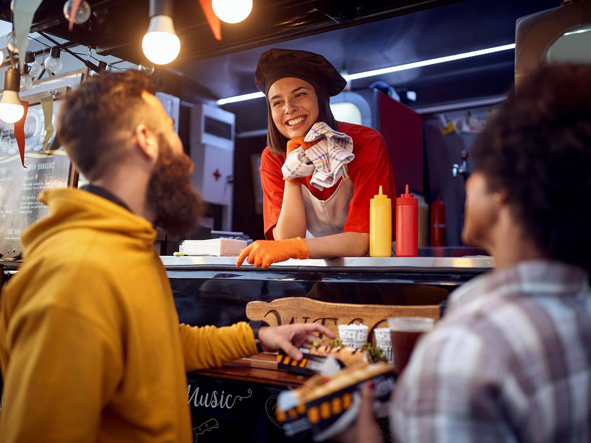 Drei Personen unterhalten sich wohlwollend an einem Imbissstand