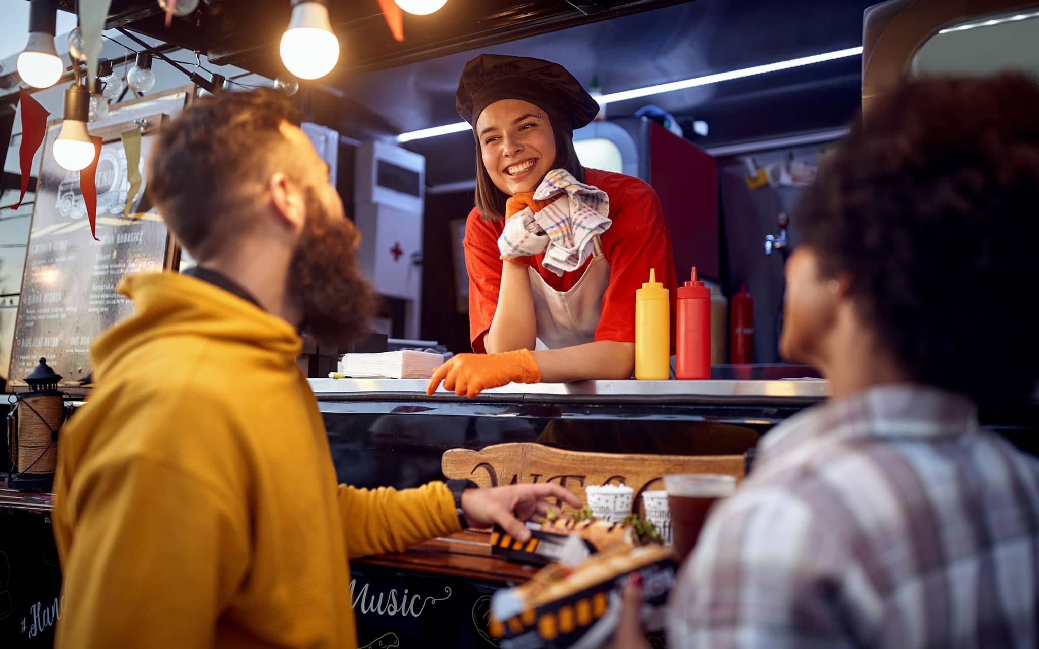Drei Personen unterhalten sich wohlwollend an einem Imbissstand