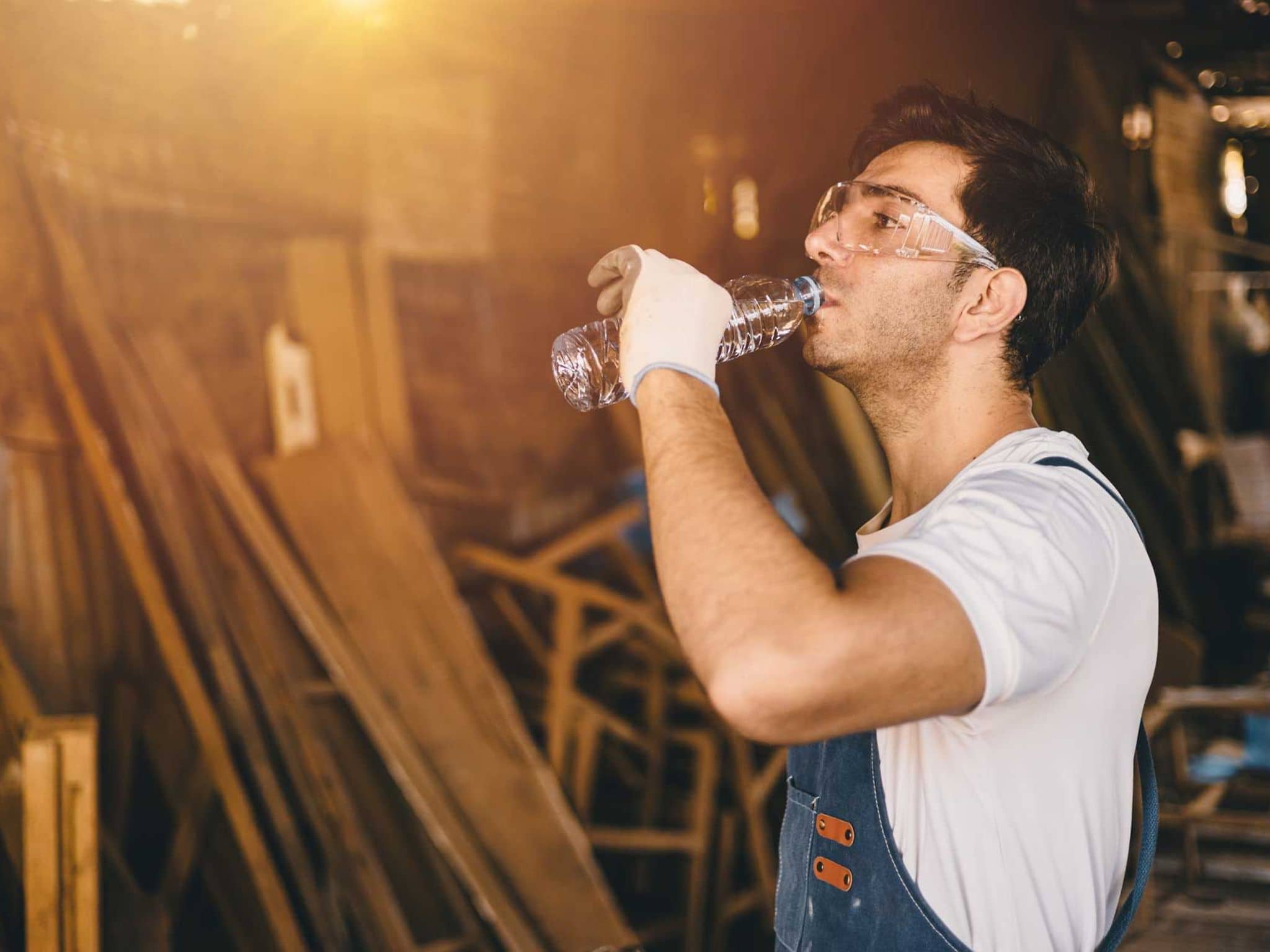 Symbolbild Hitze am Arbeitsplatz: Handwerker trinkt aus einer Flasche