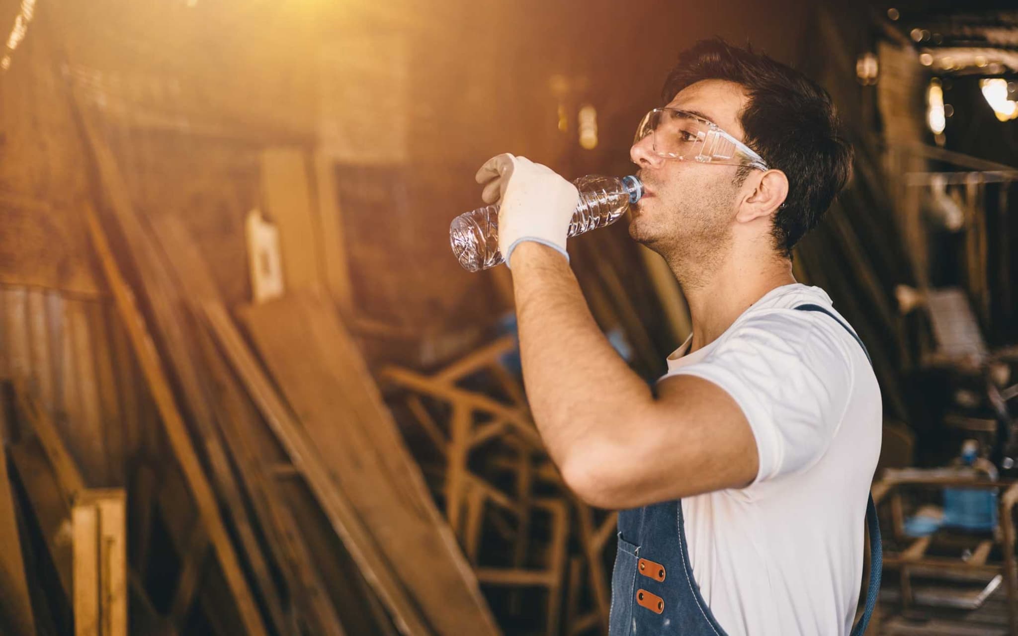 Symbolbild Hitze am Arbeitsplatz: Handwerker trinkt aus einer Flasche