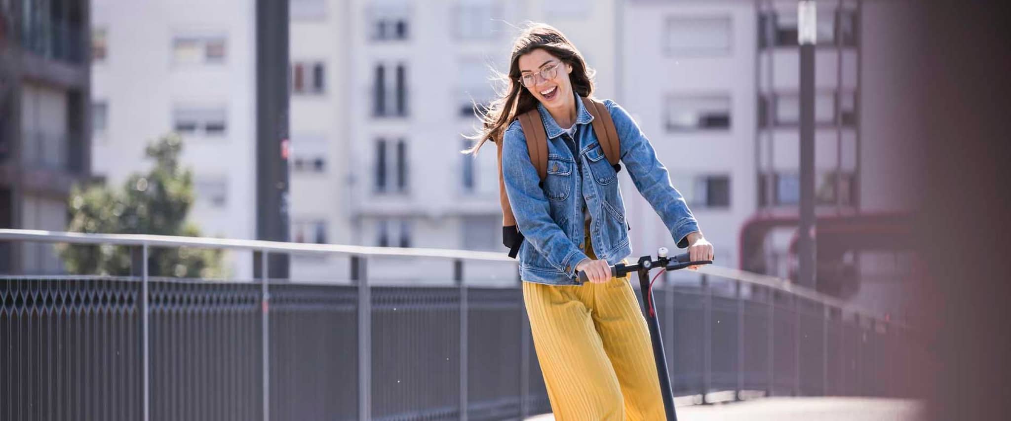 DAK Garantietarif 90: Glückliche junge Frau fährt einen E-Scooter.