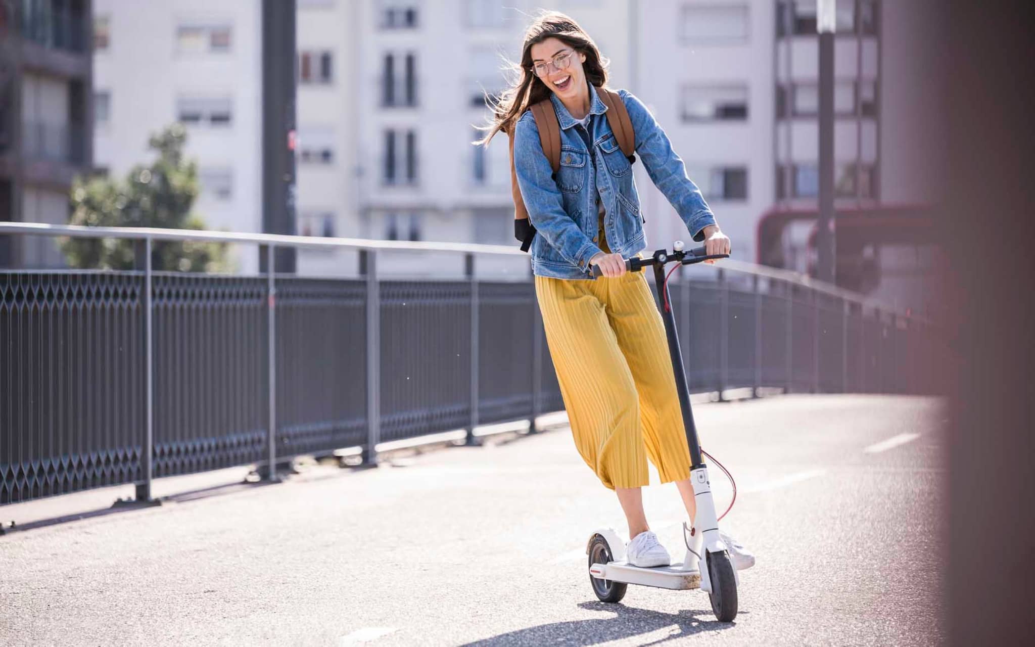 DAK Garantietarif 90: Glückliche junge Frau fährt einen E-Scooter.
