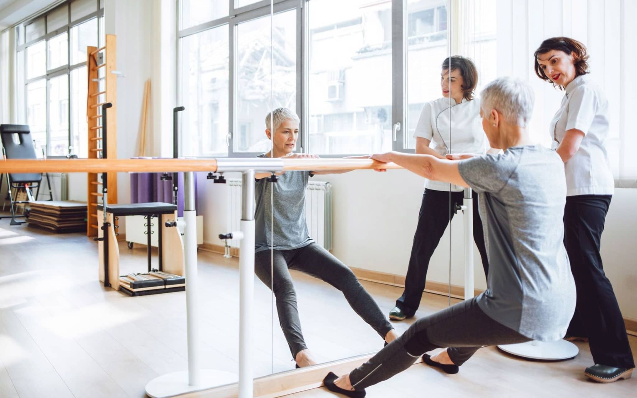 Eine Frau trainiert beim Rehasport mit Unterstützung einer geschulten Trainerin.