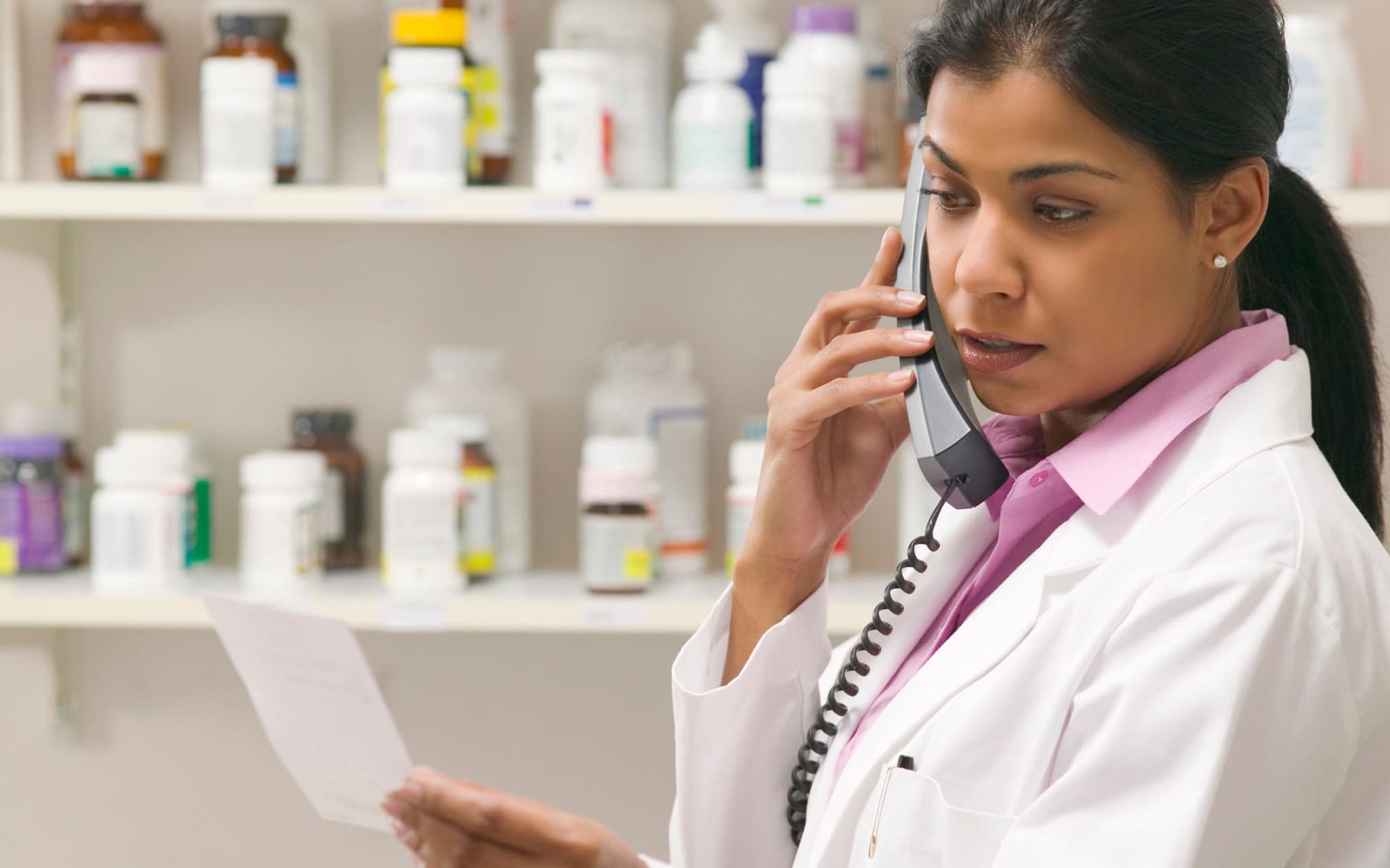 Bild: Apothekerin prüft eine Verordnung und telefoniert dabei.