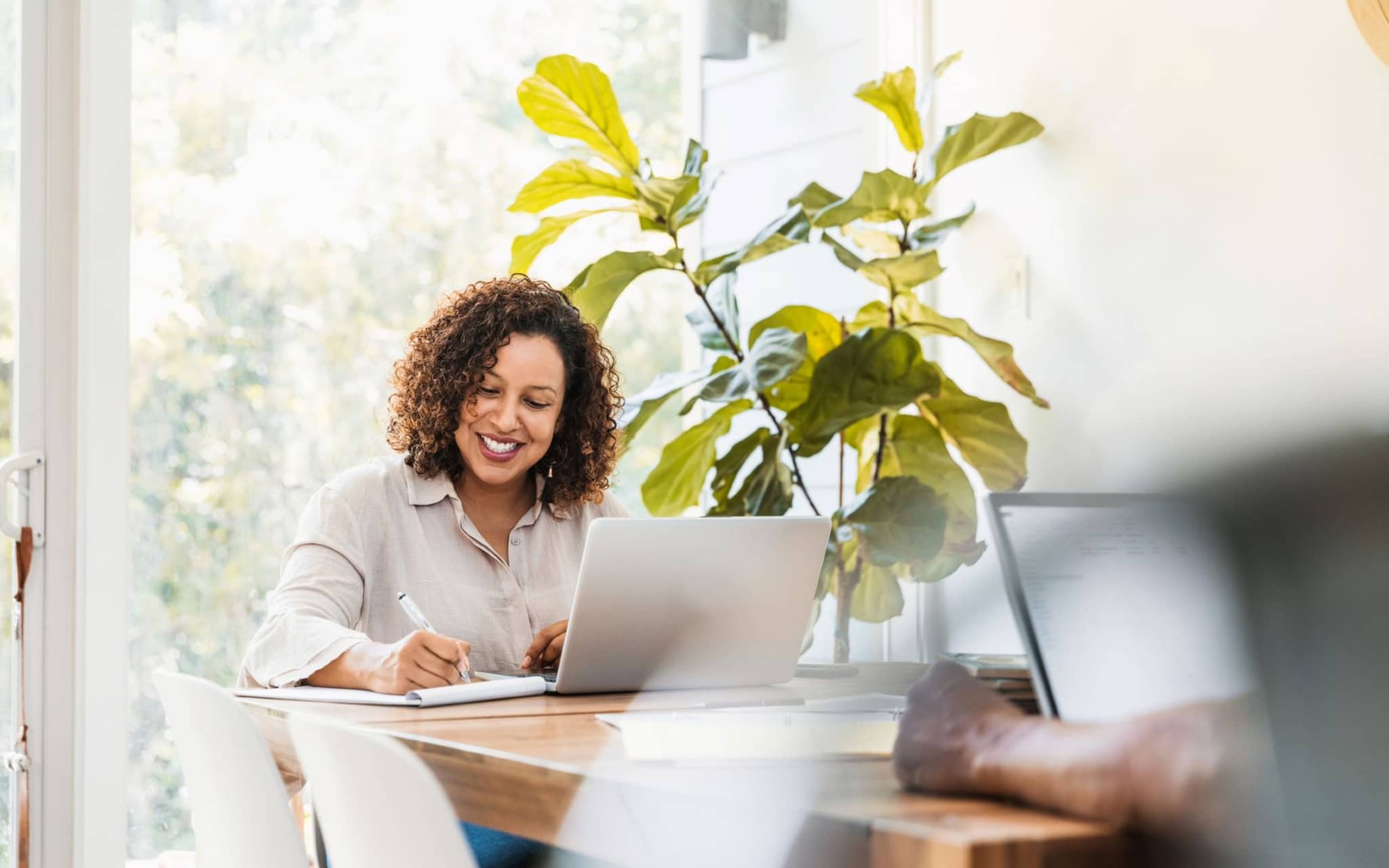 Bild: Frau mit Locken sitz an ihrem Laptop und checkt den DAK Urlaubsplaner.
