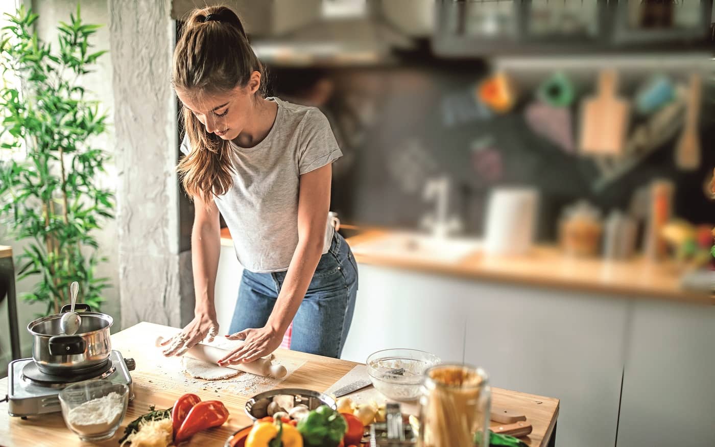 Symbolbild DAK Koch-Duell: Junge Frau rollt Teig aus in der Küche.