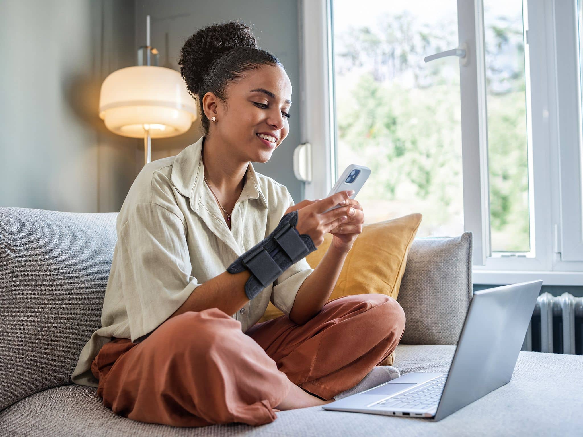 Symbolbild eVerordnung Hilfsmittel: Frau mit Bandage nutzt ihr Handy.