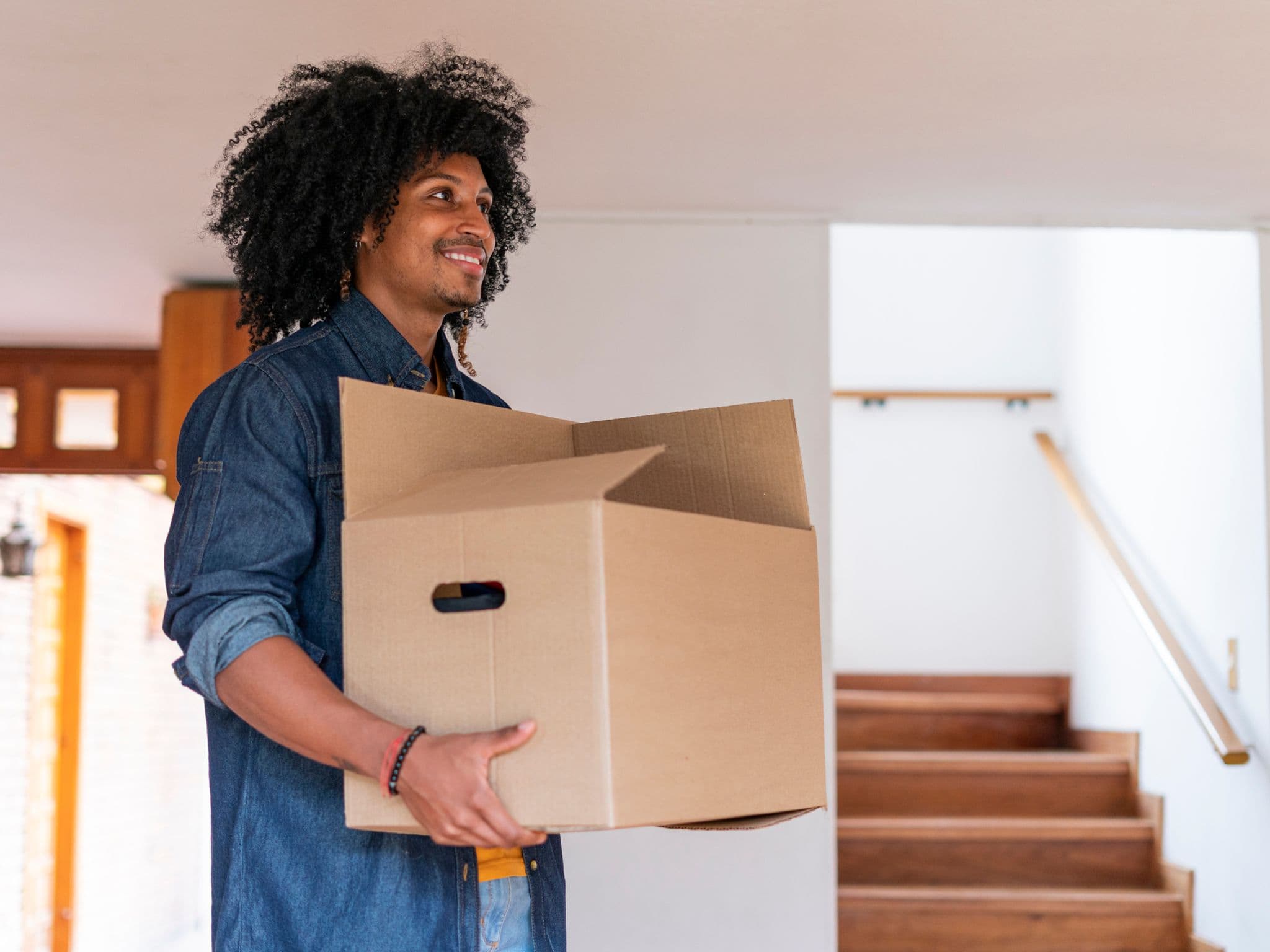 Young man is very happy entering his new house with boxes.