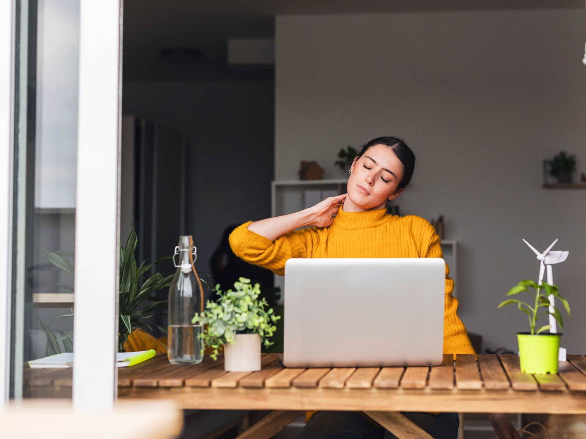 Bild: Eine Frau legt den Kopf schief und hält sich den Nacken fest