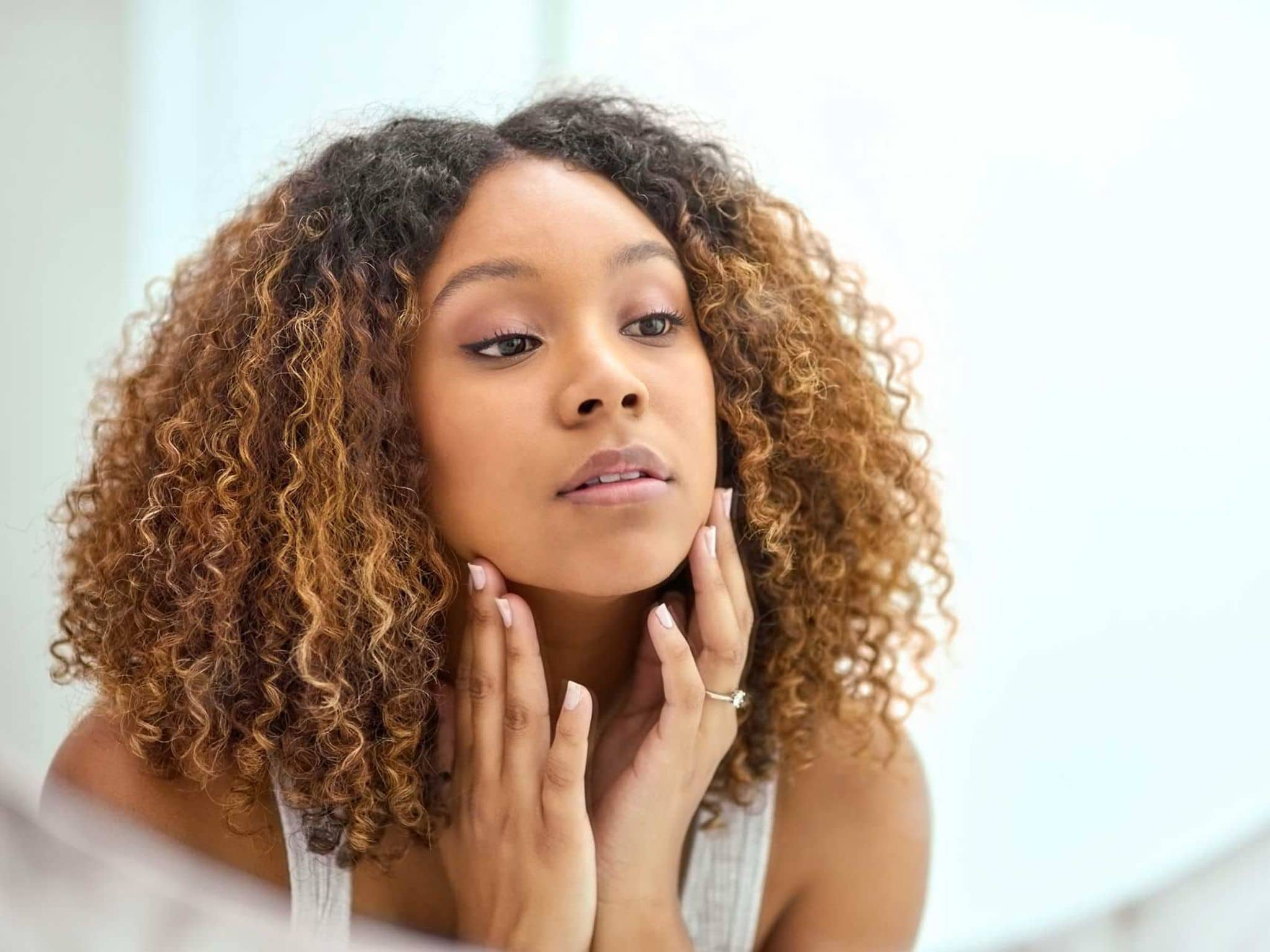 Symbolbild Cushing-Syndrom: Junge Frau blickt in den Spiegel