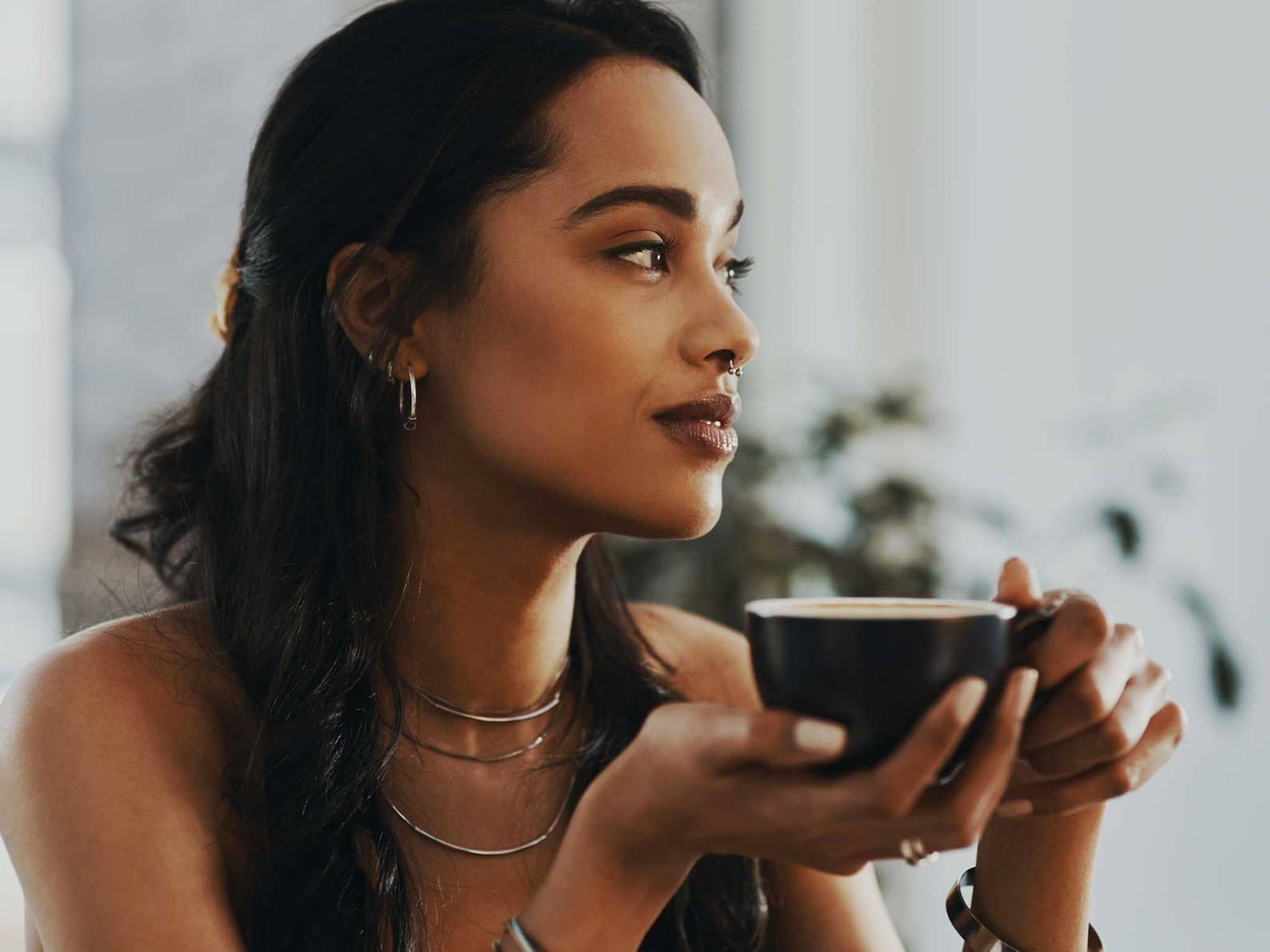 Symbolbild starke Regelschmerzen: Junge Frau entspannt bei einer Tasse Tee