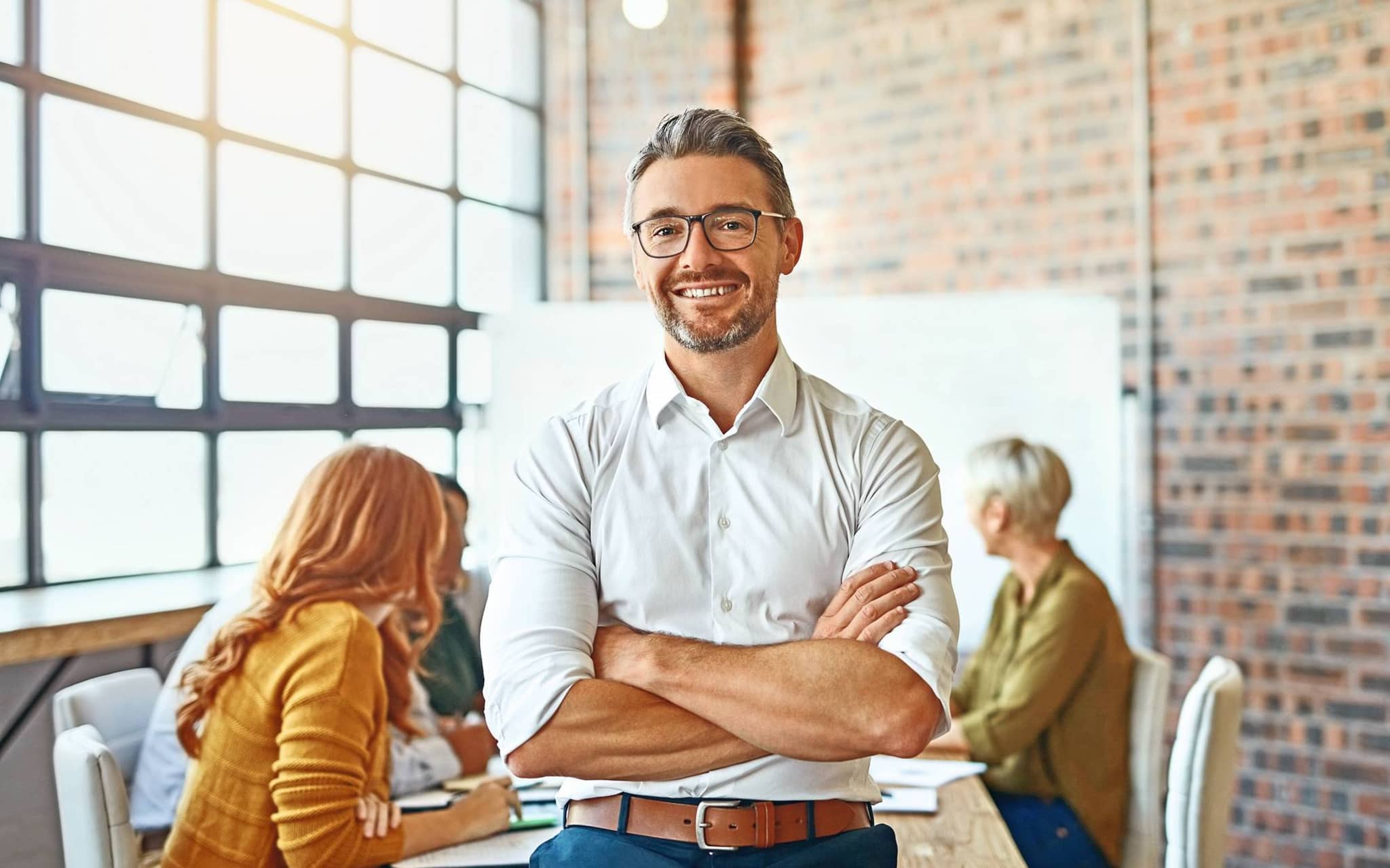 Bild: Mann mit Hemd und verschränkten Armen lächelt selbstbewusst in die Kamera.